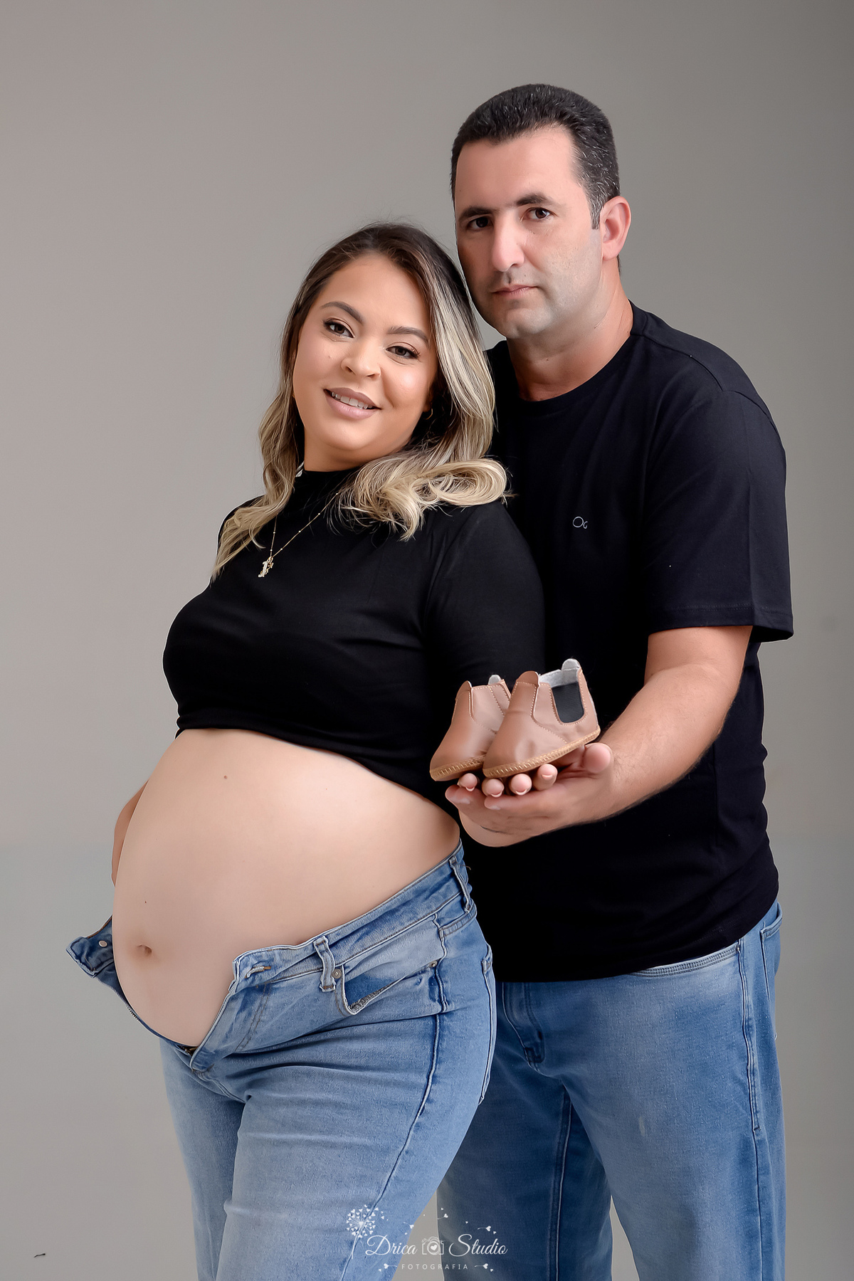 ensaio familia - ensaio gestante - mãe de 2 - irmã mais velha - ensaio em studio - xinguara -pará - mamãe  e papai usando calça jeans e camisa preta - segurando o sapatinho do bebê - foto em fundo branco 