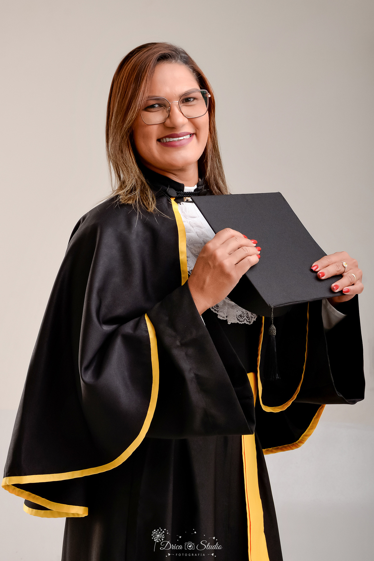 fotos formando - fotos em studio - radiologia - formatura - drica studio - formanda usando beca de radiologia -  segurando chapéu com as maos - foto em fundo branco 
