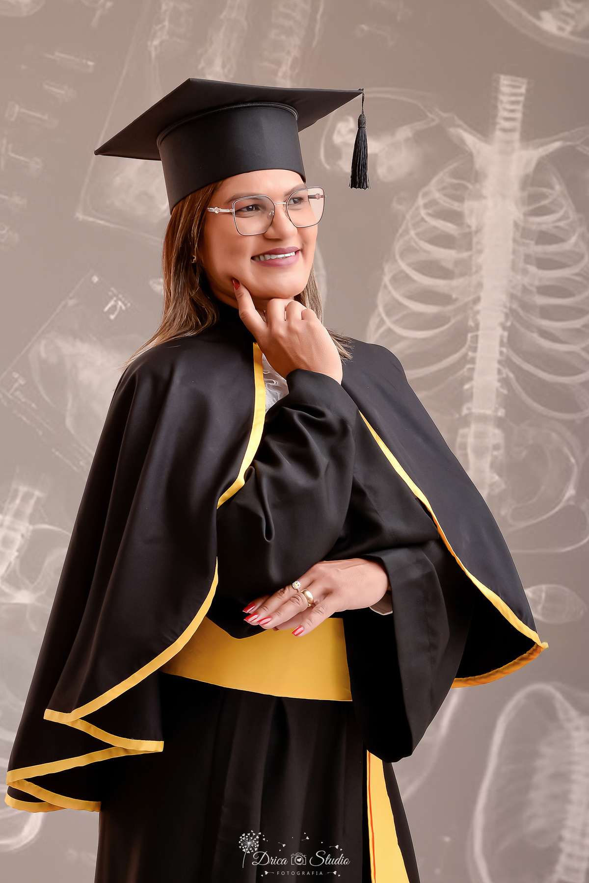fotos formando - fotos em studio - radiologia - formatura - drica studio - formanda usando beca de radiologia - ao fundo imagem de raio x para simbolizar o curso - formanda com uma das mãos no rosto - 