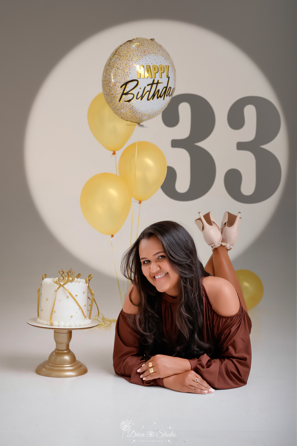 Aniversário - 33Anos - HappyBirthday - EnsaioFeminino -  EnsaioDeAniversário - aniversariante usando vestido marrom - com balões dourados ao chão e com gás helio - bolo com laços dourados - ao fundo led com numero 33 - 