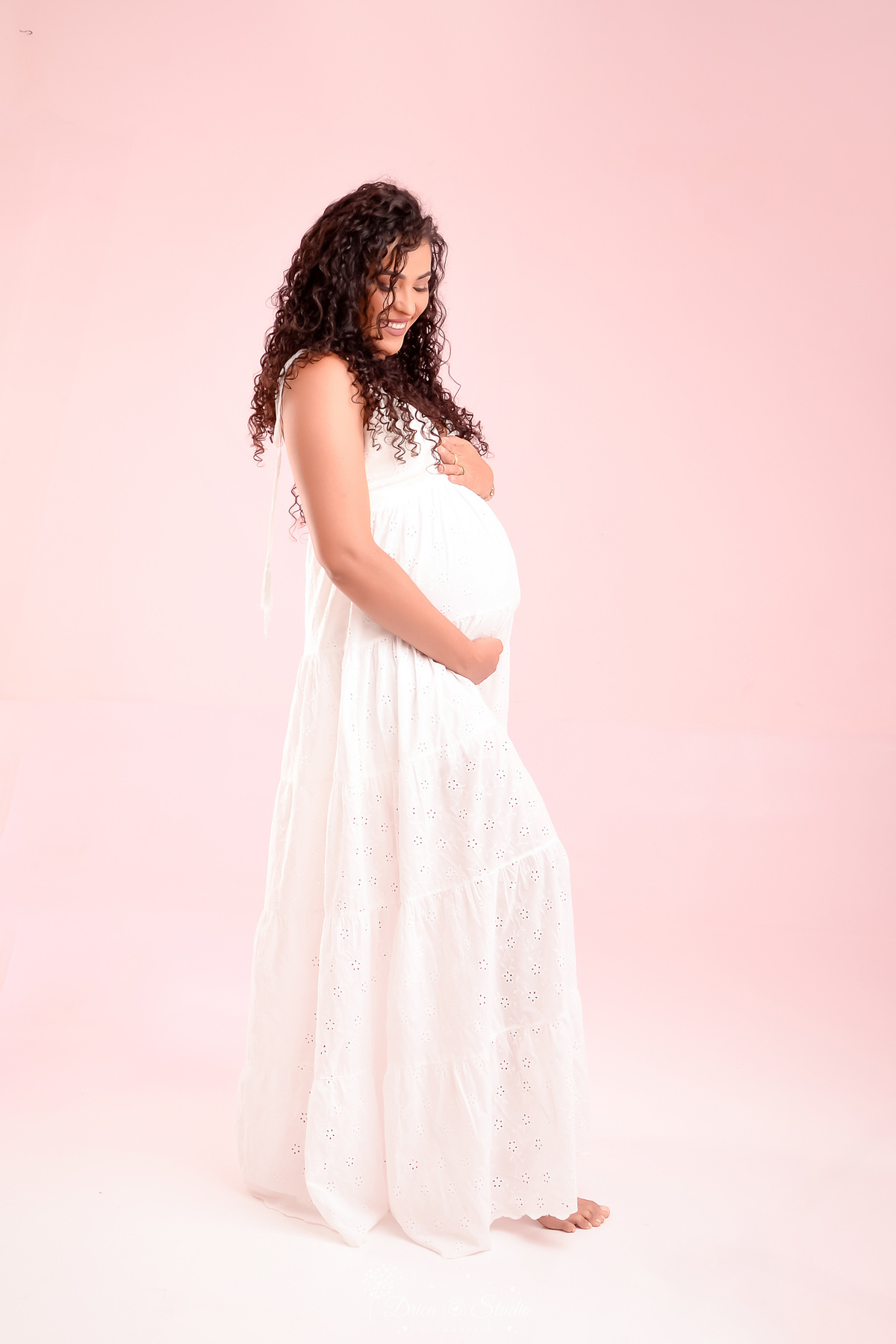 Ensaiogestante - fotos em estudio - 8 meses - gestante usando vestido londo branco - com as mãos sobre a barriga - fundo com led rosa - drica studio - xinguara - pará 