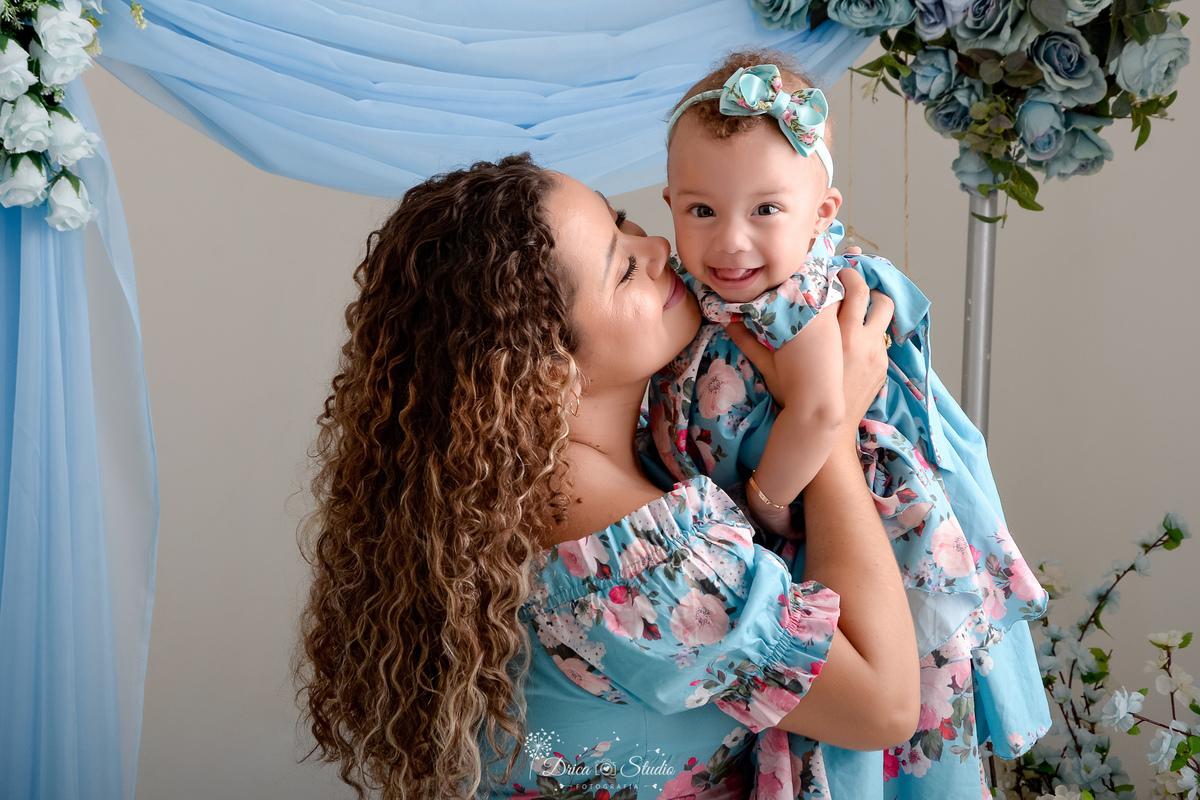 Ensaio mãe e filha - amor incondicional - mãe e filha usando roupas combinando - em tons azuis e rosas - ao fundo flores azuis 