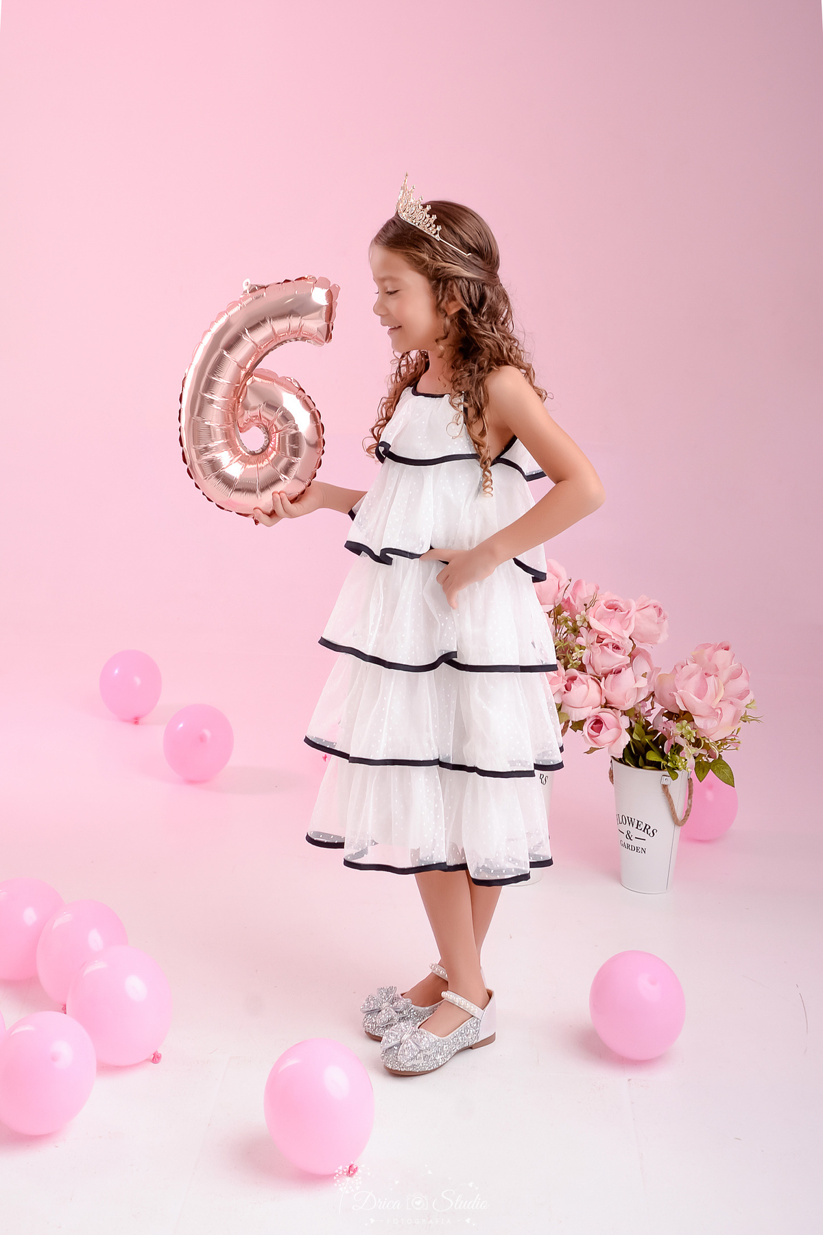 ensaio infantil - fotos de aniversario - 6 anos - menina - drica studio - xinguara - pará - fundo rosa - foto em estudio - balões rosas - flores rosas - usando vestido branco com detalhes pretos -  segurando um balão com o numero da idade - 