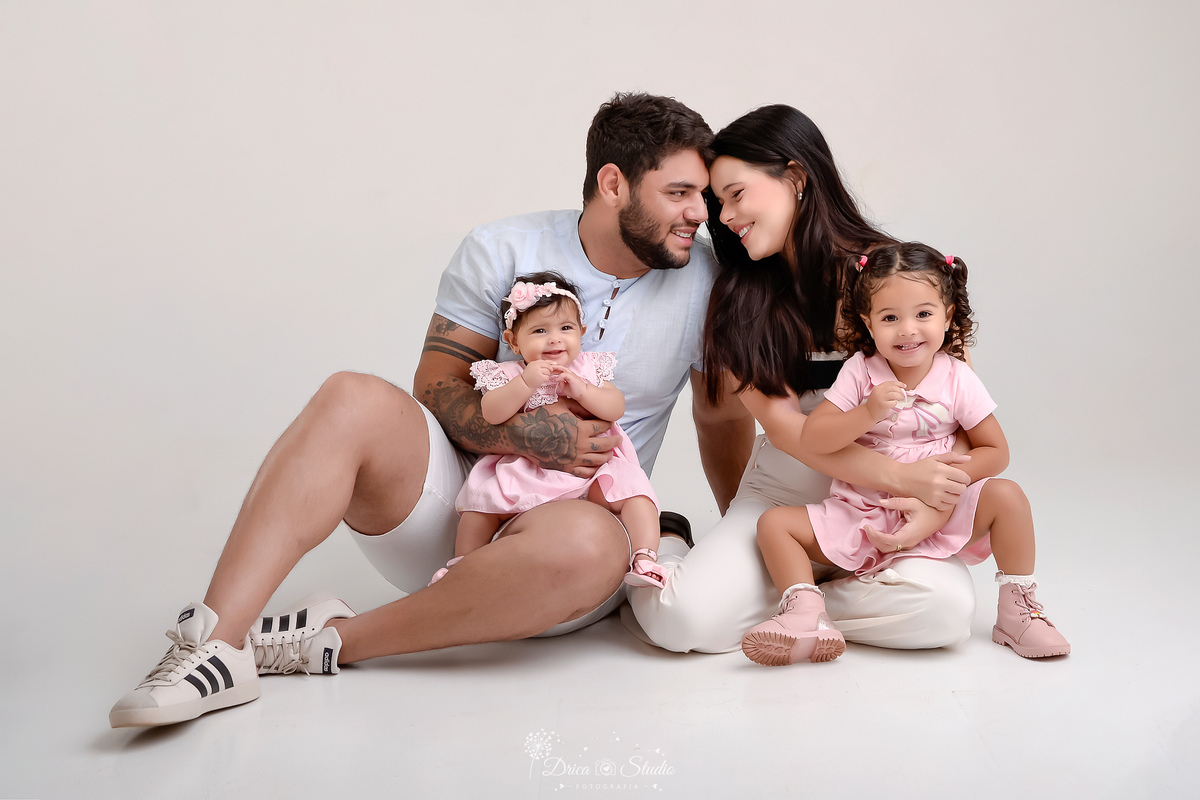 drica studio - ensaio familia - mãe pai, e filhas - familia unida - especial dia dos pais - pai segurando a filha caçula - sentados no chão - mãe sugrando a filha mais velha 
