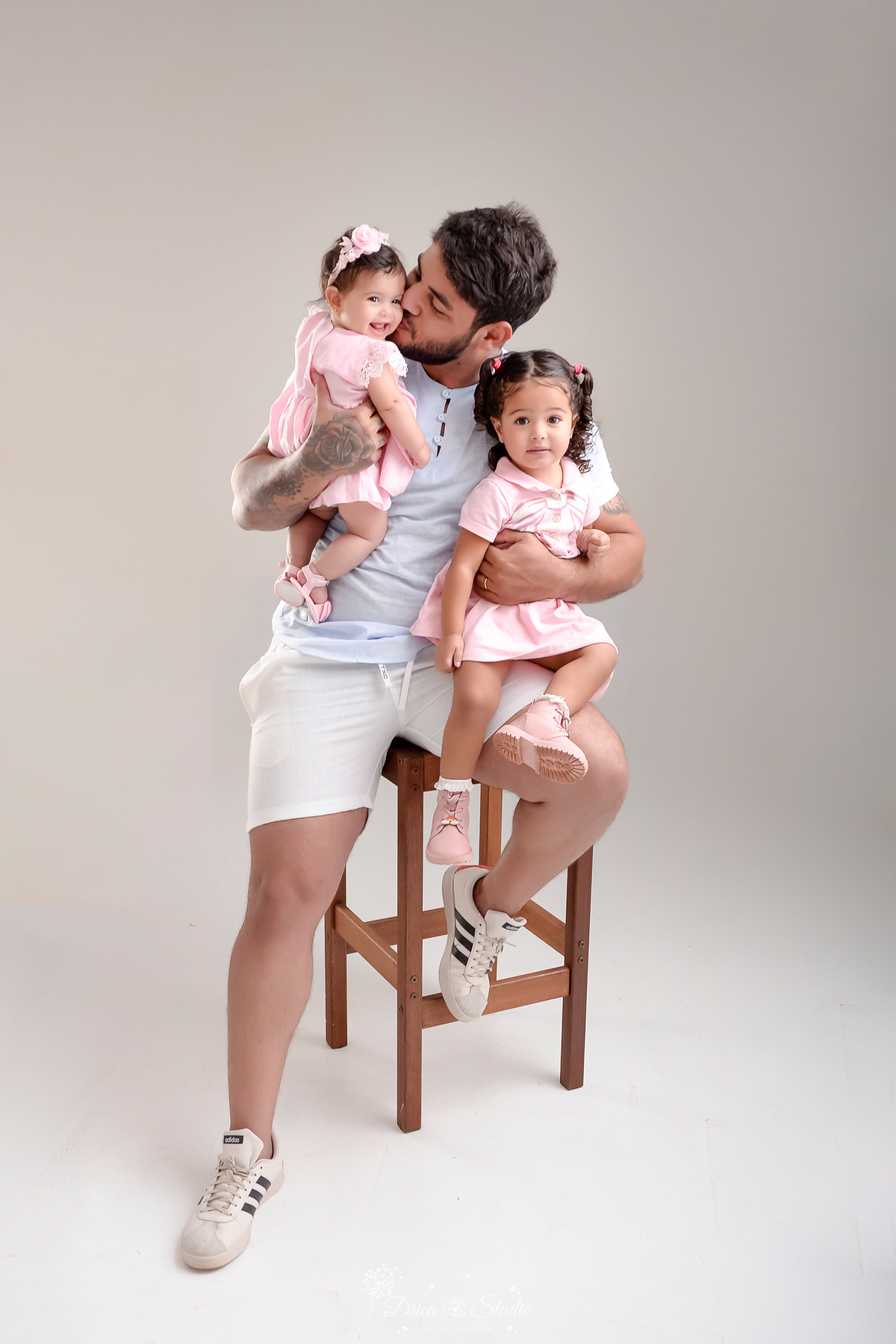drica studio - ensaio familia - oai e filhas - sentado em uma cadeira de madeira - segurando as duas filhas - foto em estudio - especial dia dos pais 