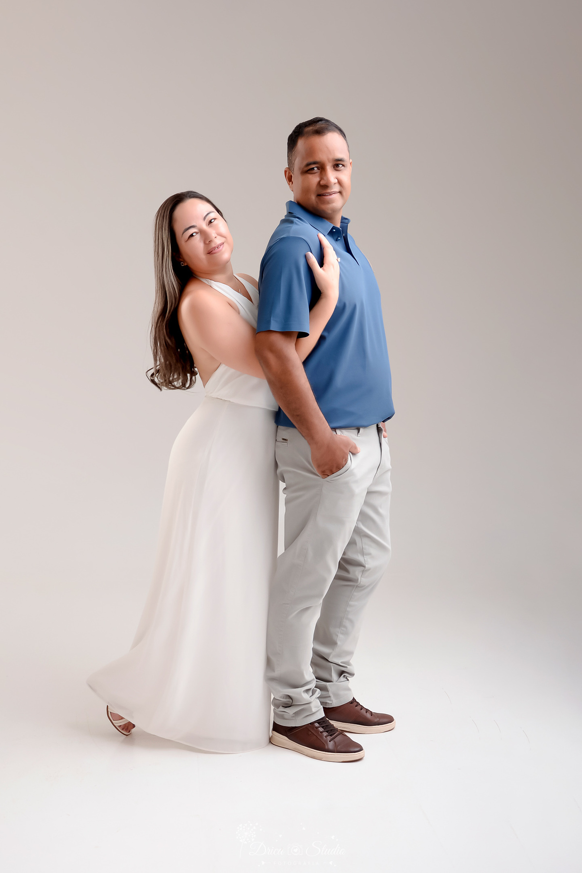 prewedding - ensaio casal - noivos - casamento - ensaio em estudio - drica studio - xinguara - pará - noivos abraçados - noiva usando vetido branco longo - noivo usando calça cinza e camisa azul - foto em fundo branco 