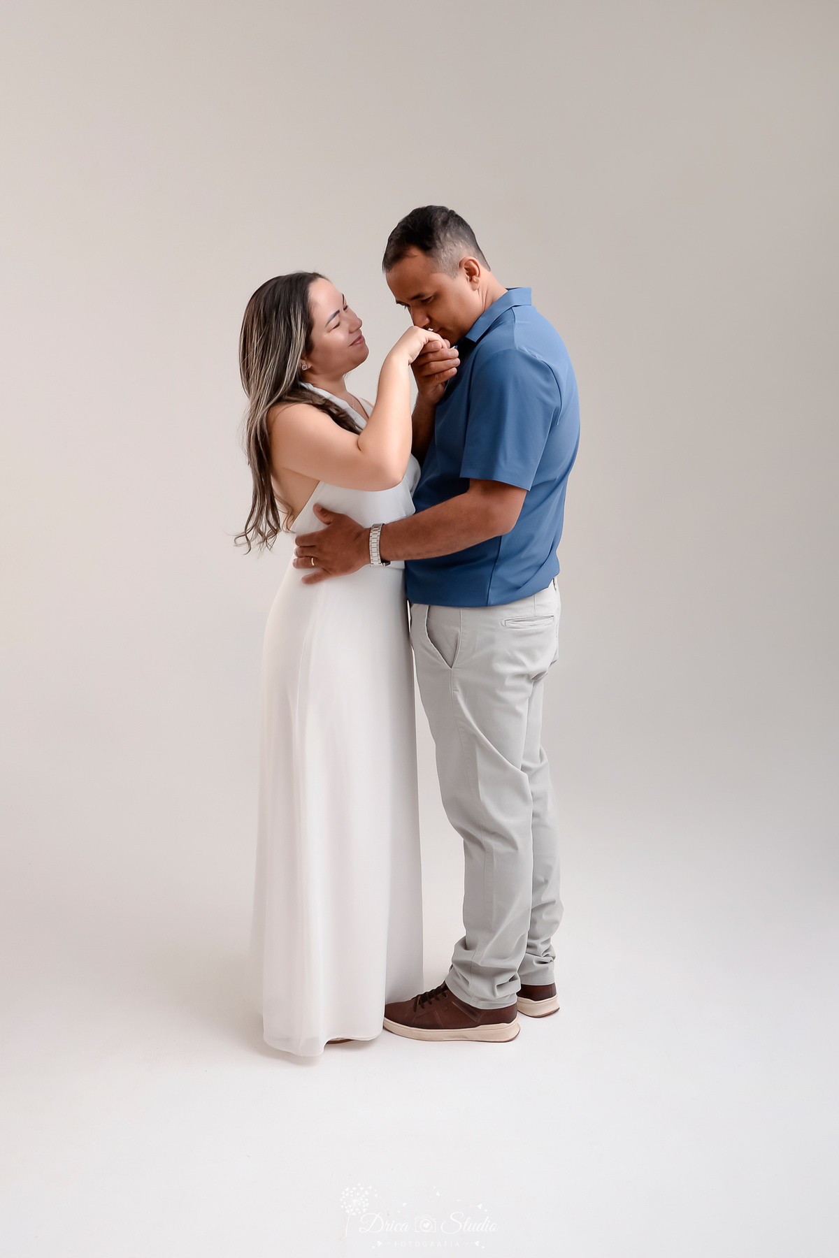 prewedding - ensaio casal - noivos - casamento - ensaio em estudio - drica studio - xinguara - pará - noivo beijando a mão da noiva - noiva usando vestido branco longo - noivo usando calça cinza e camisa azul - 