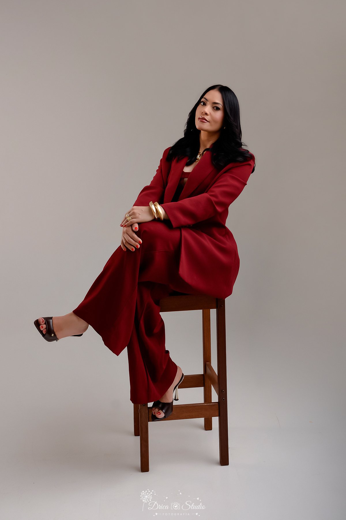 drica studio - aniversario - ensaio em estudio - fotos profissionais - xinguara - pará - usando conjunto de calça e blazer na cor vinho sentada em uma cadeira de madeira 
