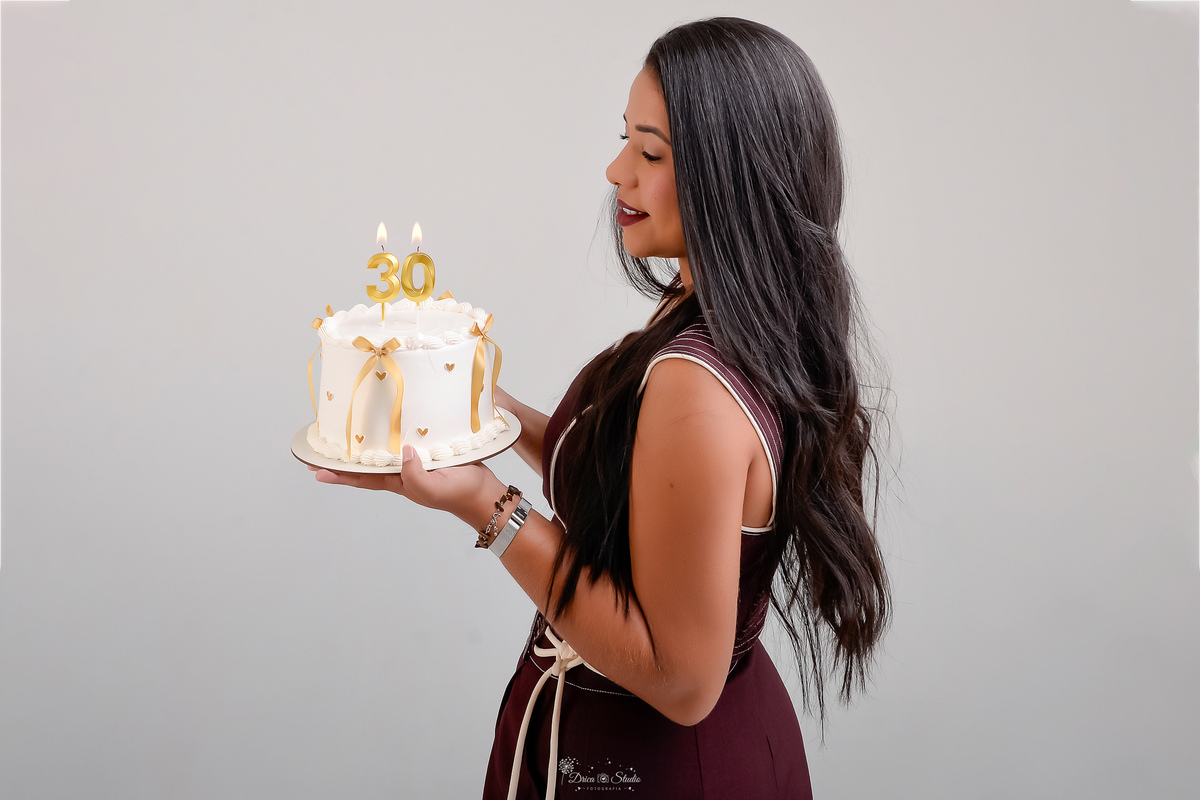 ensaio de aniversario - fotos de 30 anos - ensaio em estudio - drica studio - xinguara - pará - bolo branco - com laços dourados - velas de 30 anos - aniversariante usando conjunto  marrom - fundo branco sem detalhes - 