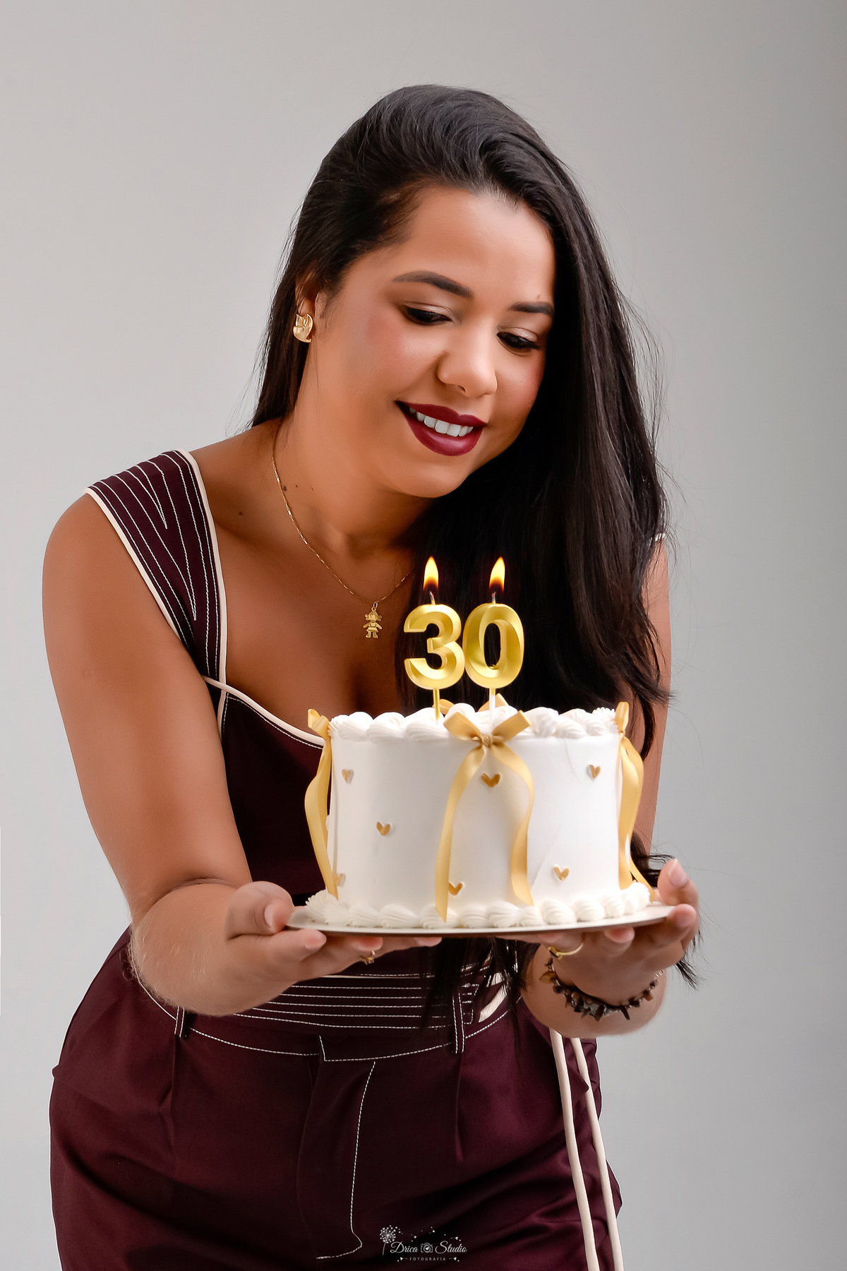ensaio de aniversario - fotos de 30 anos - ensaio em estudio - drica studio - xinguara - pará - bolo branco com laços dourados e mini corações dourados - vela de numero 30 - aniversáriante usando conjunto marrom - 
