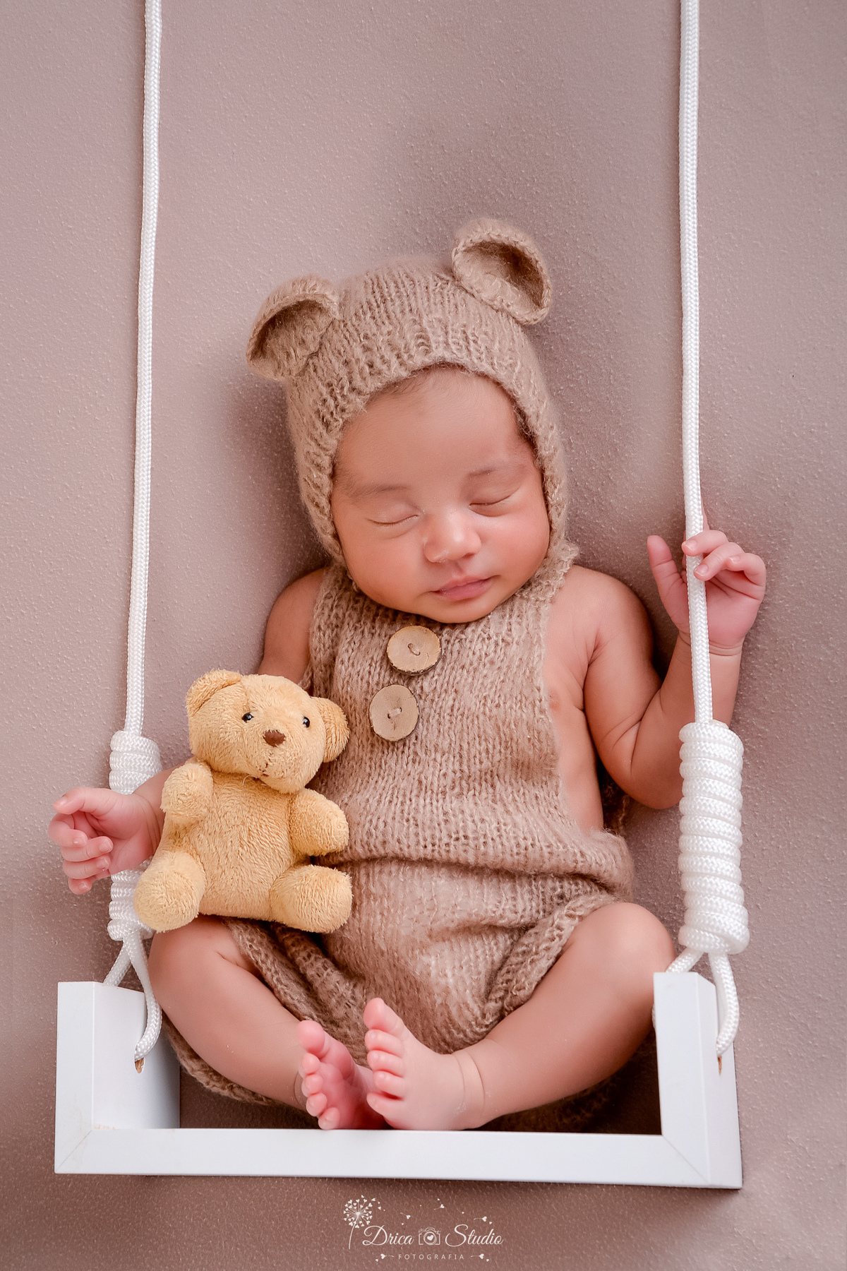 -newbornboy -bebêmenino -primeirosdias -recémnascido- dricaStudio -Xinguara - em um mini balanço branco - usando roupinha marrom de ursinho - segurando um ursinho nas mãos - 