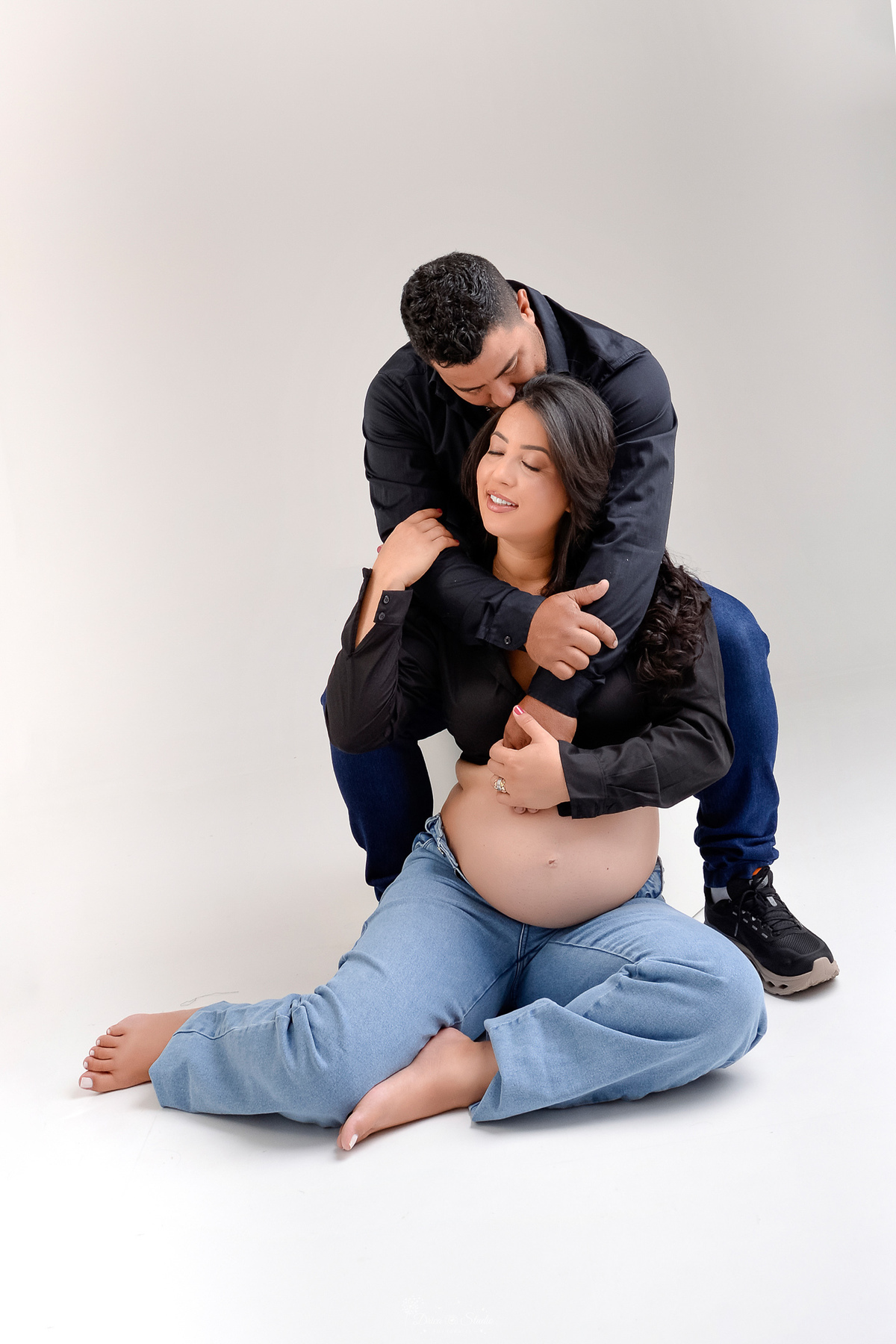 -ensaiogestante -fotografiagestante  -gravidez -maternidade - casal usando calça jeans e camisa preta - fundo branco - 