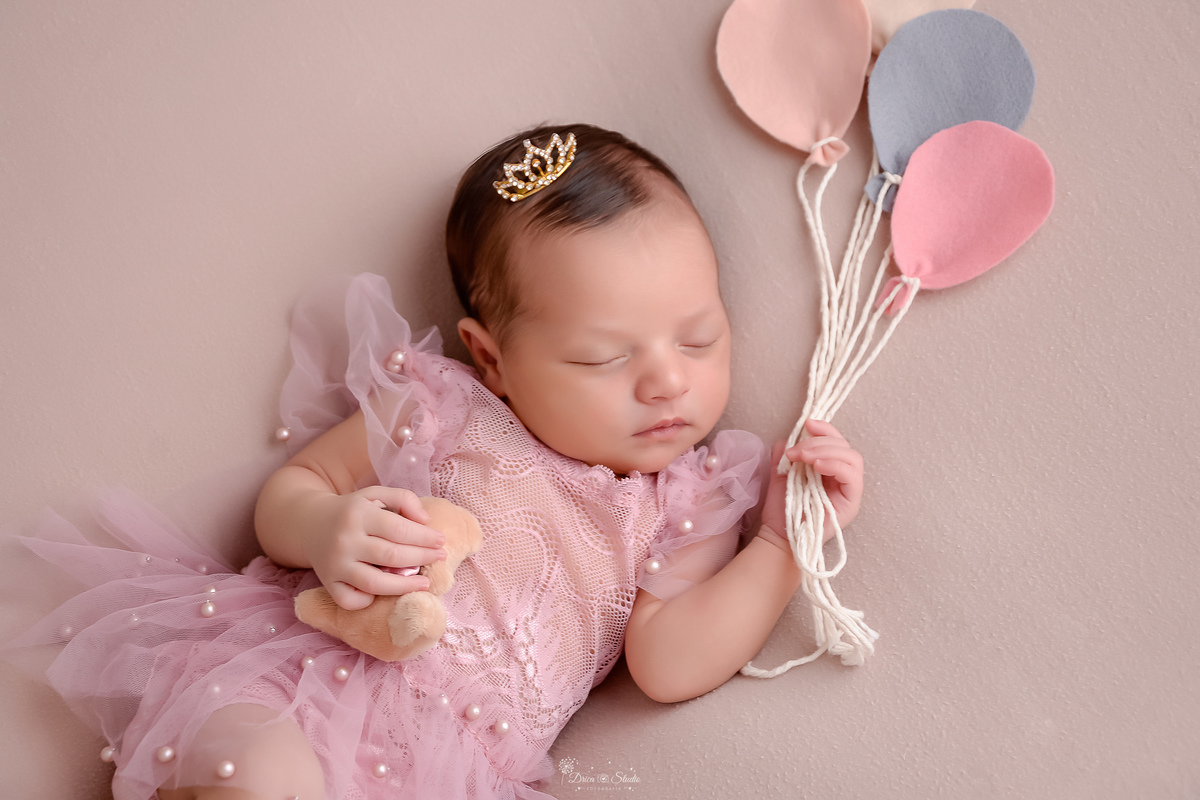 Newborn - primeiros dias - recém nascida - ensaio newborn - drica studio - xinguara - bebê segurando balões - usando vestido rosa - com mini coroa na cabeça - 