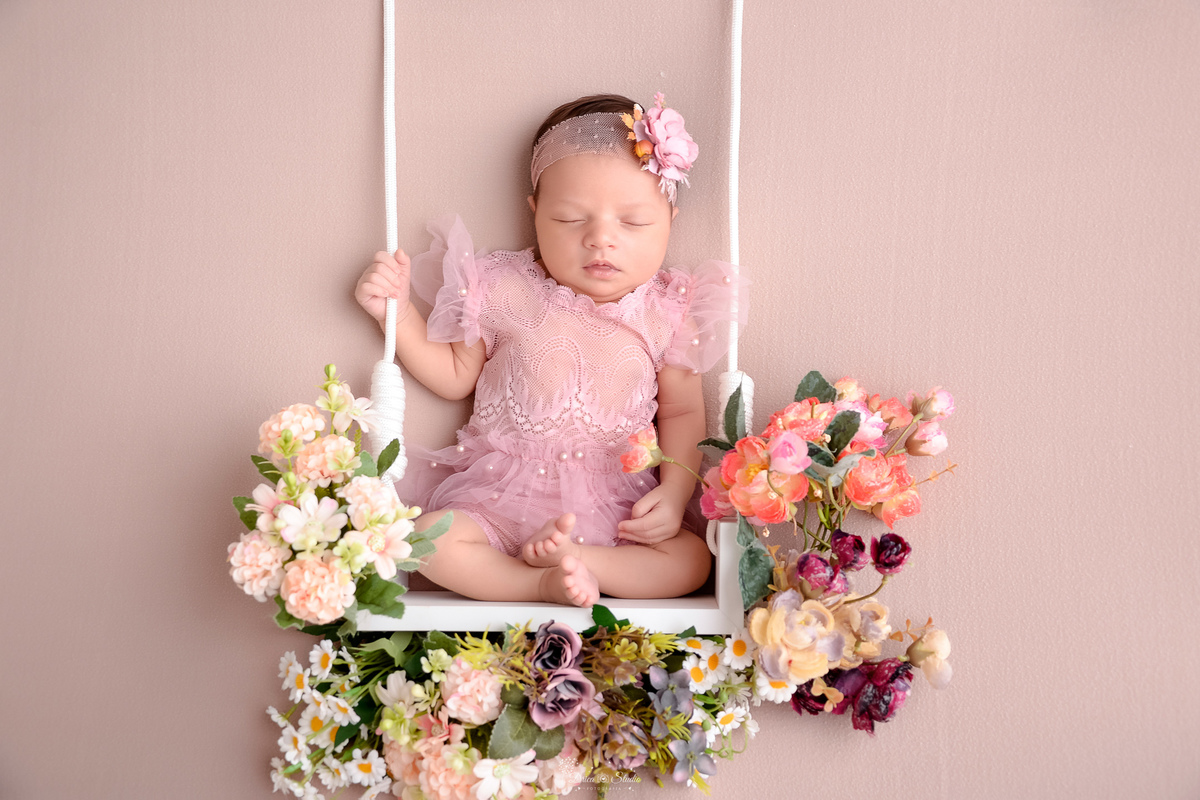 Newborn - primeiros dias - recém nascida - ensaio newborn - drica studio - xinguara - balanço com flores - bebê usando vestido rosa com laço de flor na cabeça -
