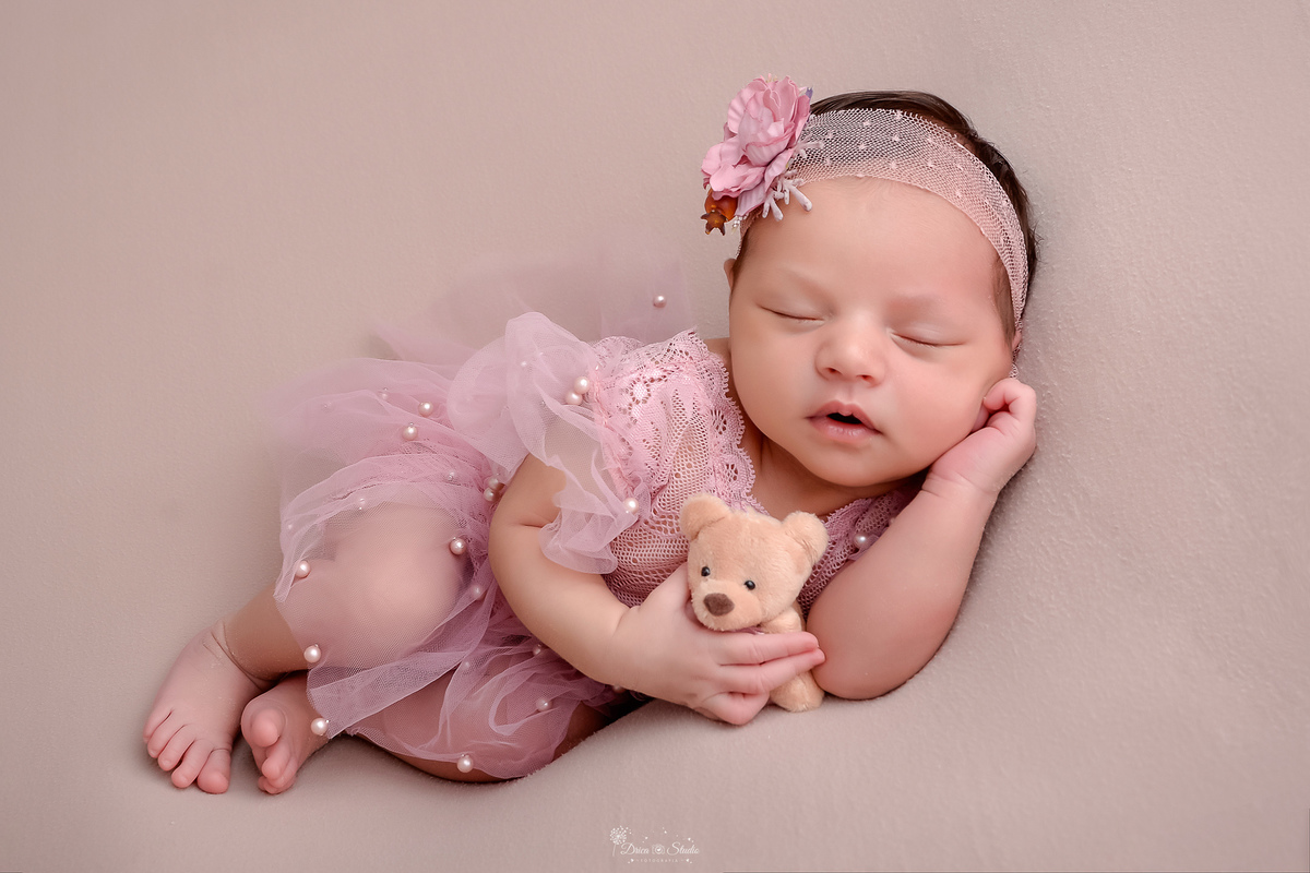 Newborn - primeiros dias - recém nascida - ensaio newborn - drica studio - xinguara - bebê usando vestido rosa com laço de flor - segurando ursunho - 