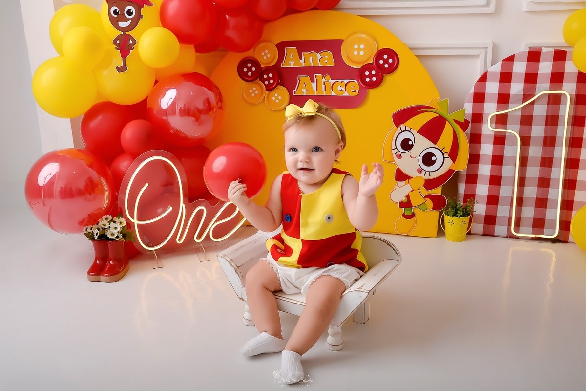 drica studio - smash the cake - 1 ano - ensaio infantil - acompanhamento mensal - xinguara - pará - tema emilia - cenário com balões vermelhos e amarelos - 1 de led - one de led - saci - emilia - bebe sentada em baquinho - usando roupinha da emilia 