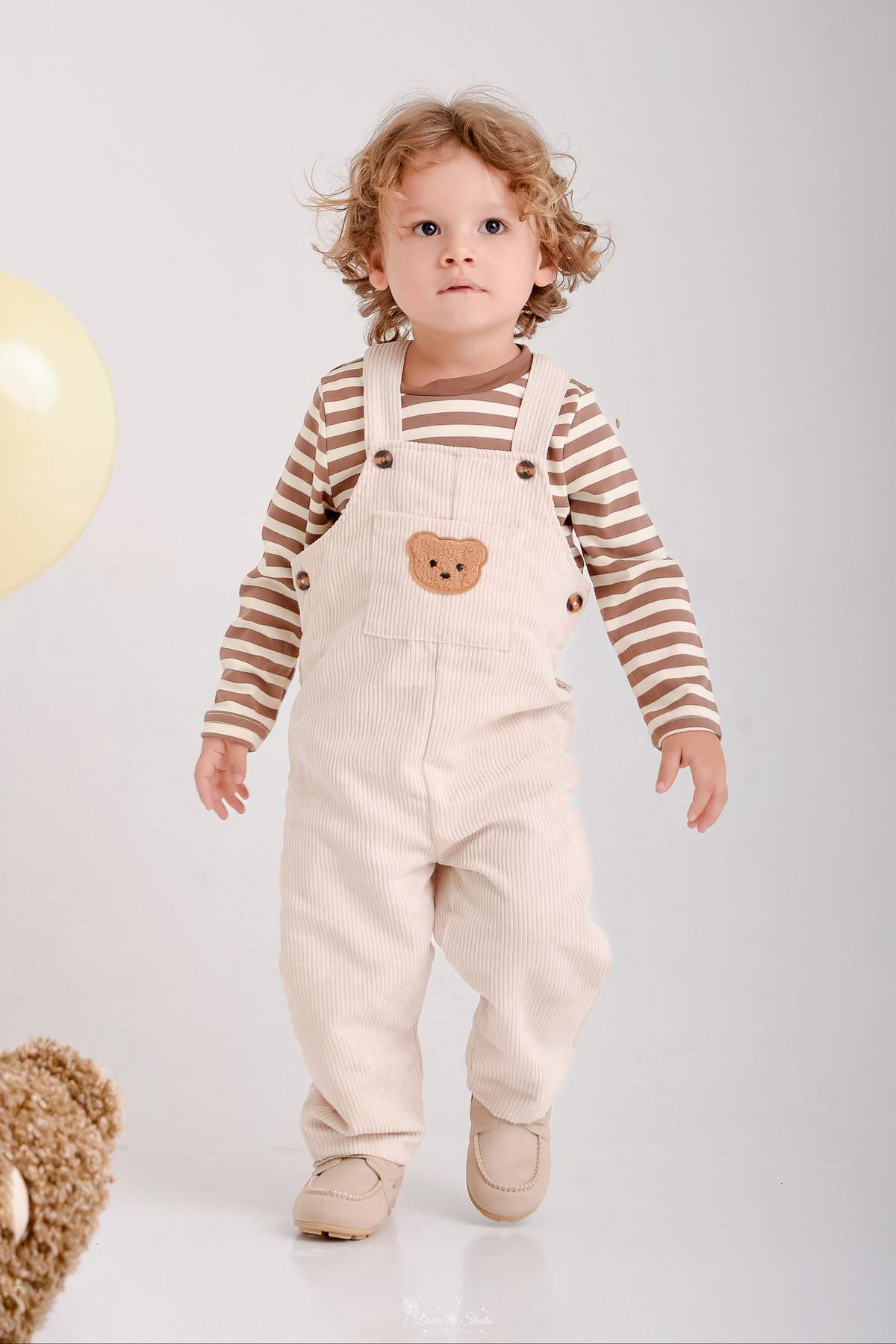 ensaio de aniversario - bebê de 2 anos - ensaio em estudio - drica studio - xinguara - pará - bebê em pé - foto em fundo branco - bebe usando macacão bege com camisa listrada - 
