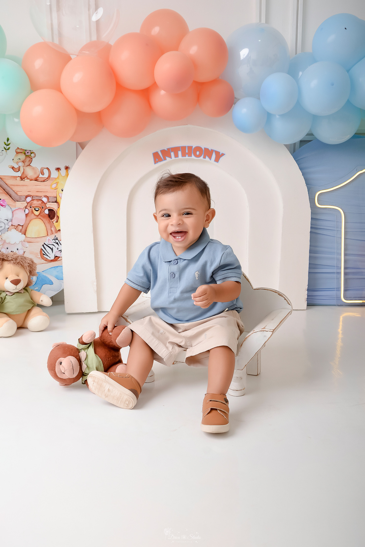 Drica studio - ensaio infantil - ensaio de 1 ano - smash the cake - arca de noé - acompanhamneto mensal - cenário de arca de noé - bebe sentado em um baquinho de madeira branco - ursinhos de pelucia 