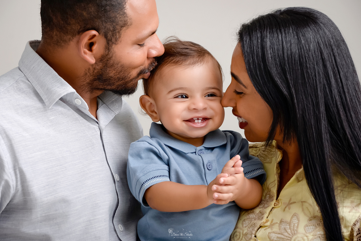 Drica studio - ensaio infantil - ensaio de 1 ano - smash the cake - arca de noé - acompanhamneto mensal - mãe, pai e filho - bebe batendo palmas e sorrindo enquanto recebe um beijo de seus pais 