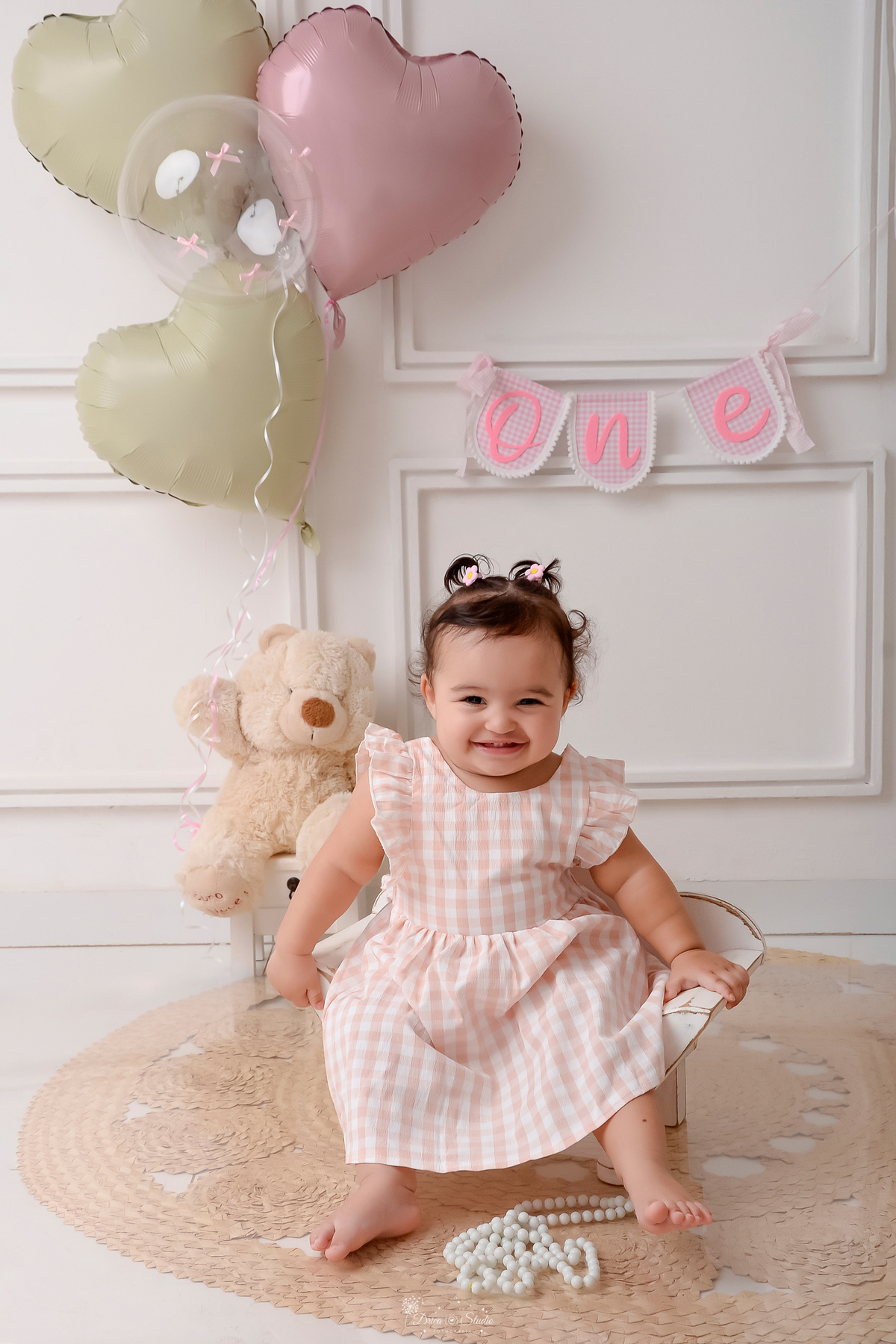Drica studio - smash the cake - ensaio familia - 1 aninho - ensaio em estúdio - bebe sentada em um baquinho branco - ao fundo um ursinho de pelucia segurando balões - nome one na parede - 
