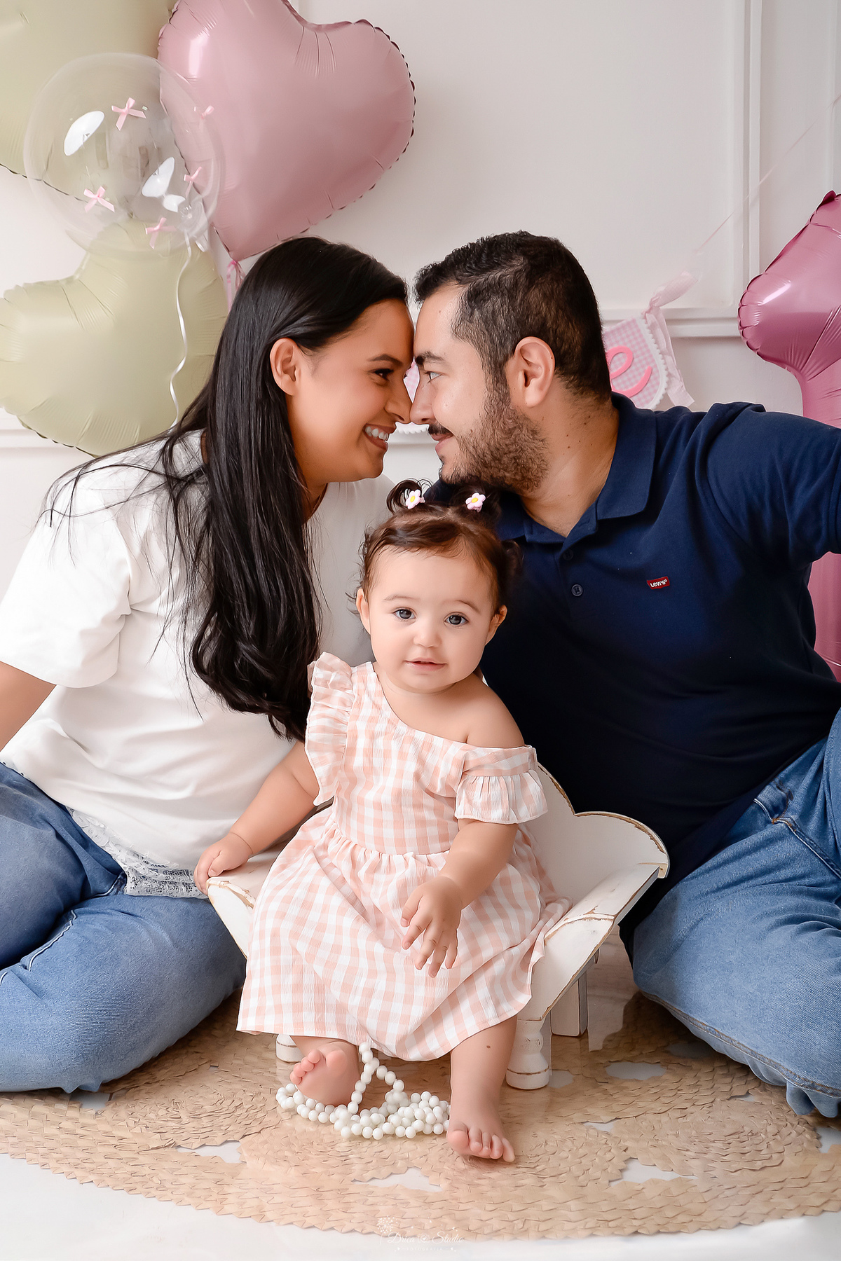 Drica studio - smash the cake - ensaio familia - 1 aninho - ensaio em estúdio - mãe, pai, e filha - bebe sentada e um baquinho de madeira branco - pai e mãe se olhando - balão de numero 1 - pai usando camisa azul - mãe usando blusa branca 