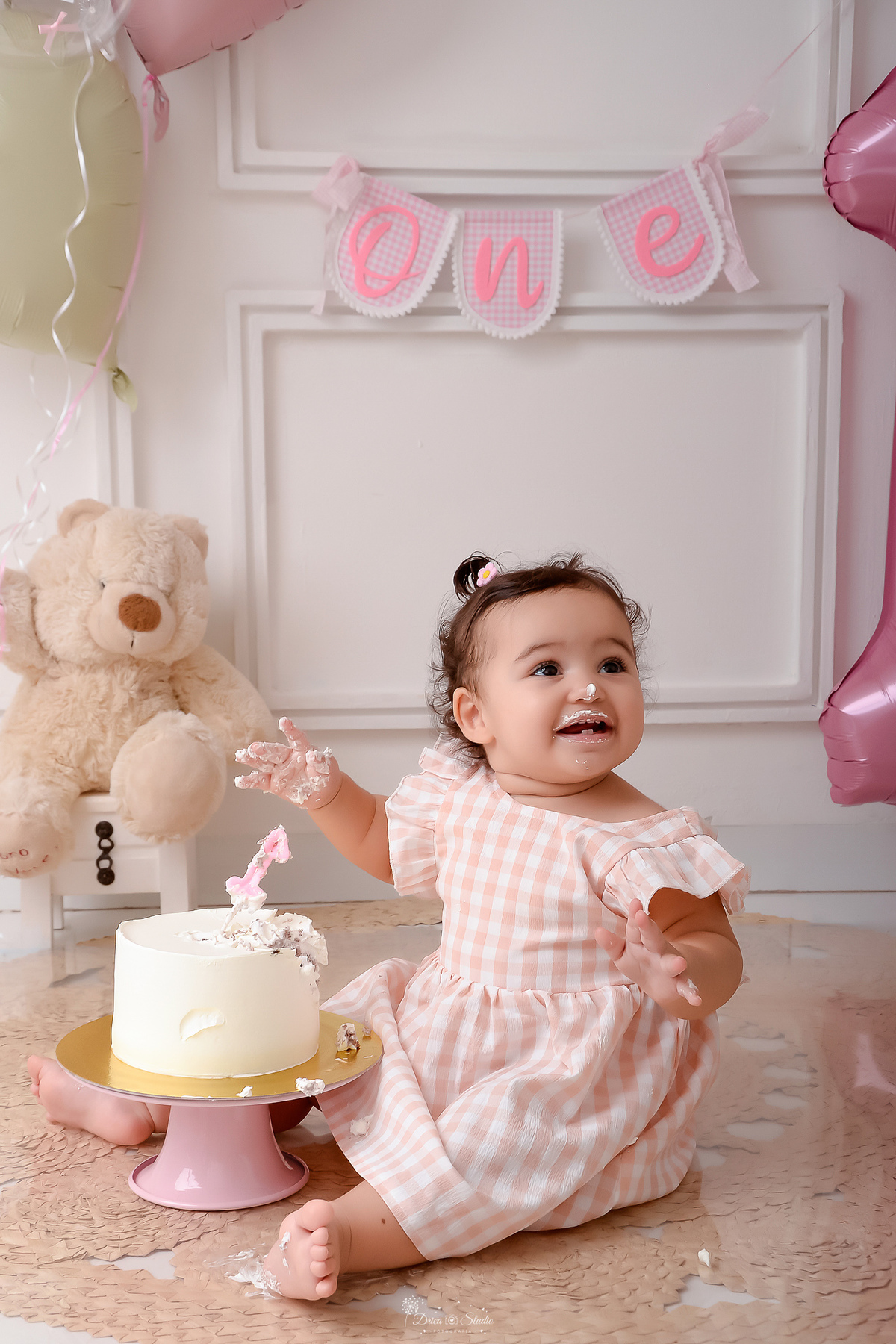 Drica studio - smash the cake - ensaio familia - 1 aninho - ensaio em estúdio - bebe com as mãozinhas sujas de bolo - balão de numero 1 - bolo com vela de numero 1 ursinho de pelucia ao fundo - one na parade - balões de coração 