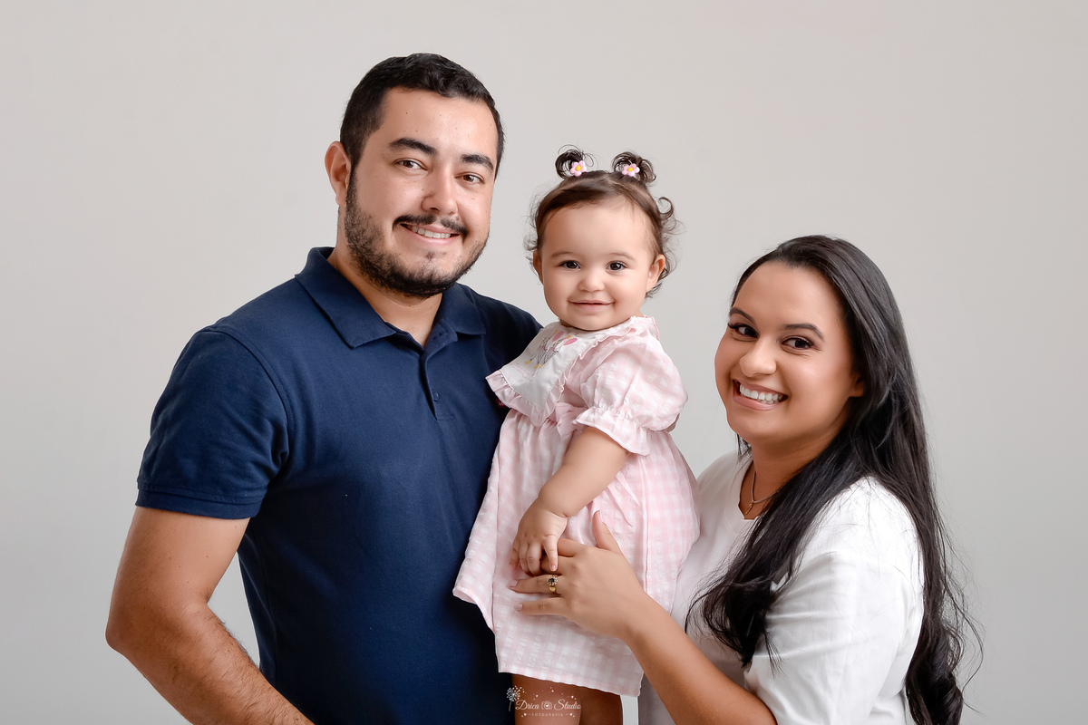 Drica studio - smash the cake - ensaio familia - 1 aninho - ensaio em estúdio - mãe, pai e filha - foto em fundo branco - pai usando camisa azul escuro - filha usando vestido rosa - mãe usando blusa branca -  