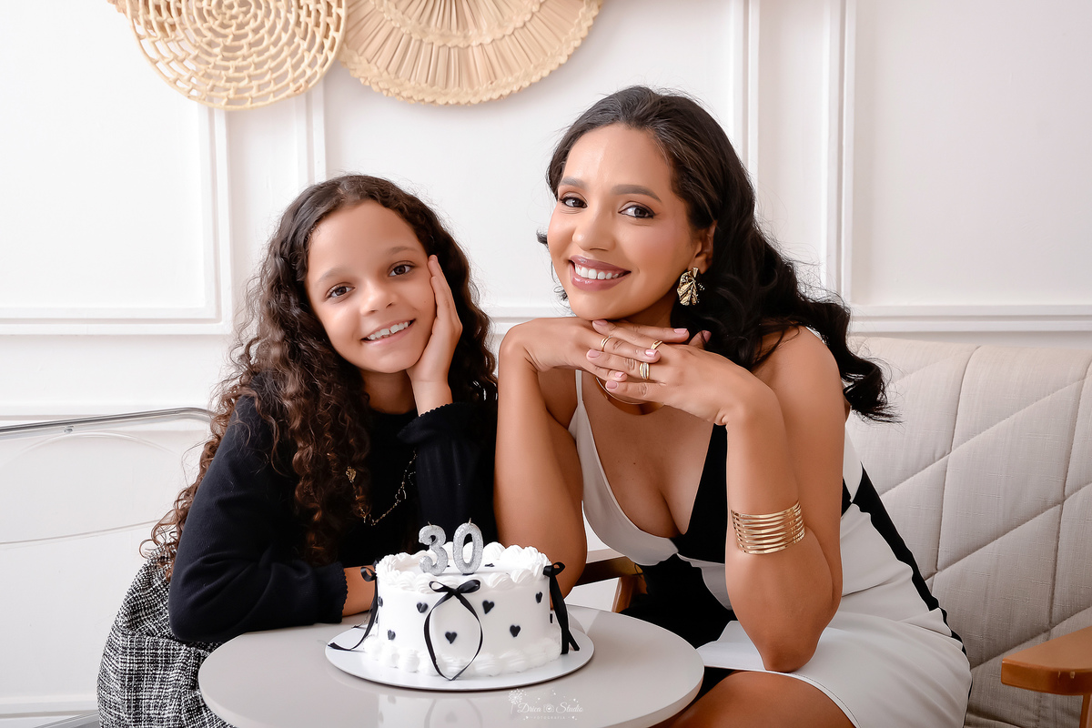 drica studio - xinguara - pará - ensaio de aniversário - 30 anos - trintou - fotos em estudio - mãe e filha - sentadas em poltrona - com bolo com velas com a idade da mãe - filha com a mãezinha no rosto - 