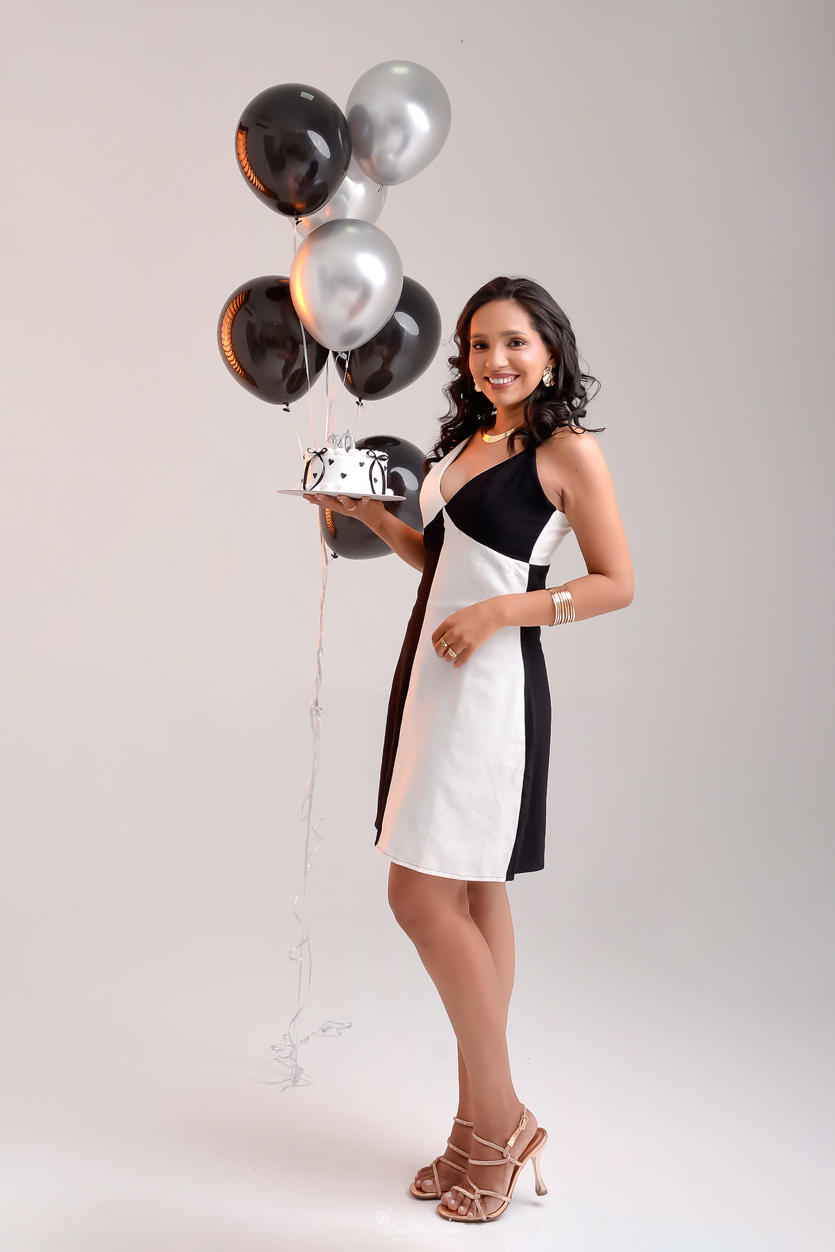 drica studio - xinguara - pará - ensaio de aniversário - 30 anos - trintou - fotos em estudio - foto em fundo branco - com balões de  gás helio pretos - usando vestido preto e branco - segurando bolo branco com detalhes preto - 
