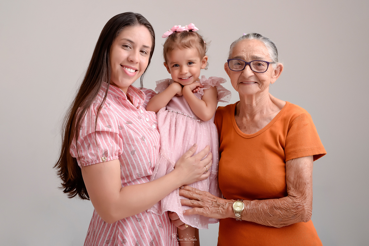 Drica studio - ensaio familia - ensaio de 2 anos - fotos em estudio - mãe, filha e bizavó - mãe e filha usando vestidos rosas - bizavó usando vestido laranja - foto em fundo branco 