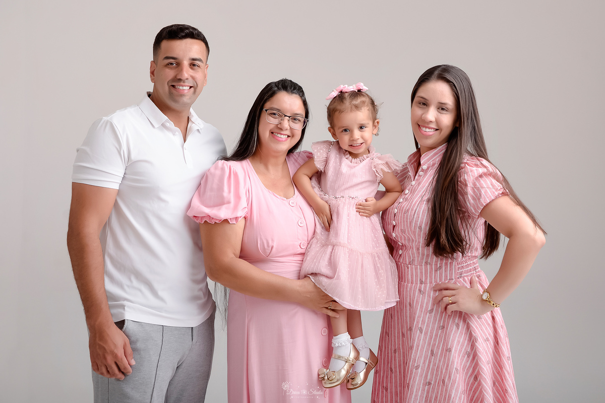 Drica studio - ensaio familia - ensaio de 2 anos - fotos em estudio - mãe, pai e filha com sua avó parterna - avó, mãe e criança usando vestidos rosas - pai usando camisa branca - bebê com as mãozinhas na cintura - foto com fundo branco - 