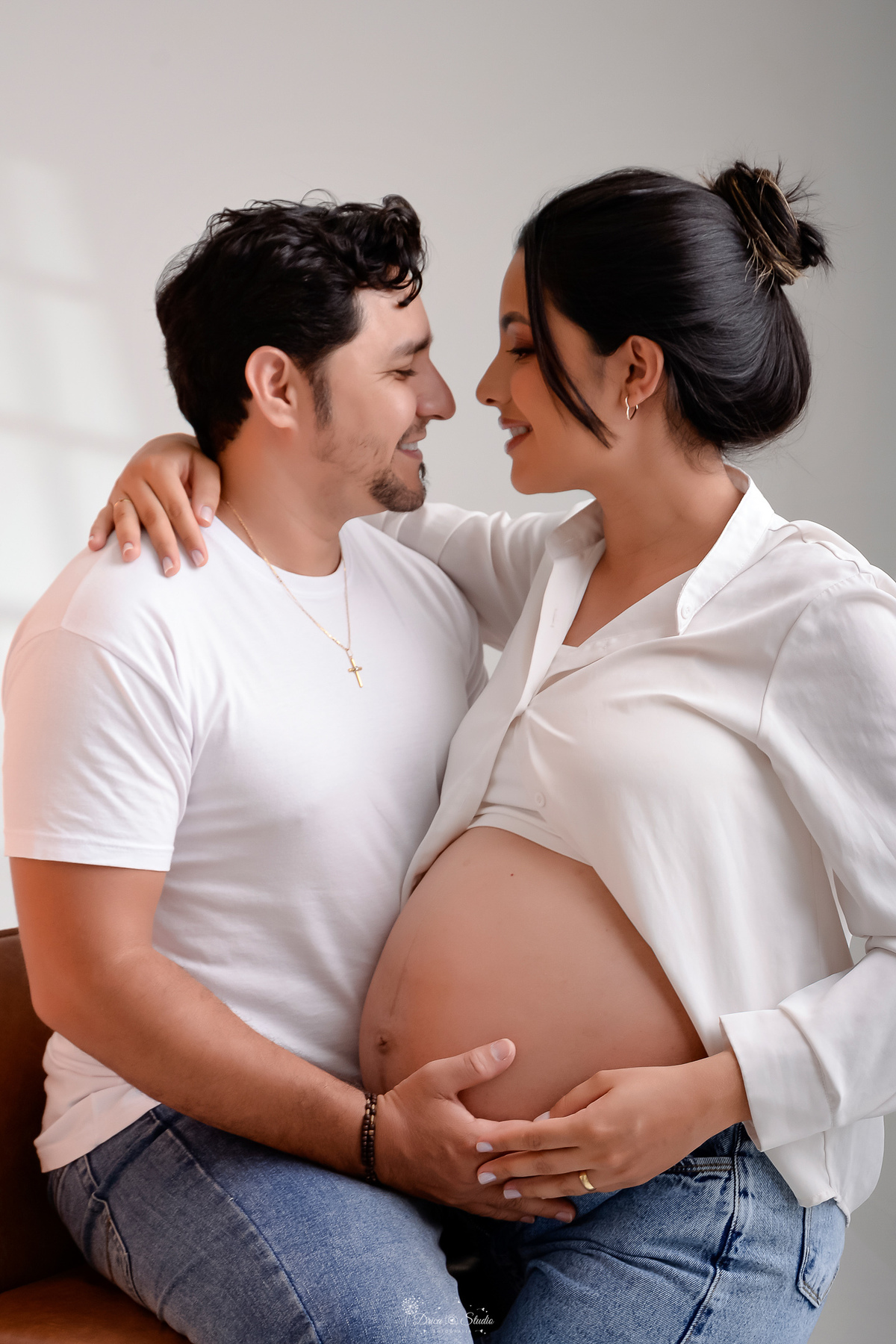 drica studio - xinguara- pará - ensaio gestante - mamãe de primeira viagem - fotografia de gestante - baby boy - papai e mamãe - casal usando blusas brancas e calças jeans - foto com o fundo branco - 