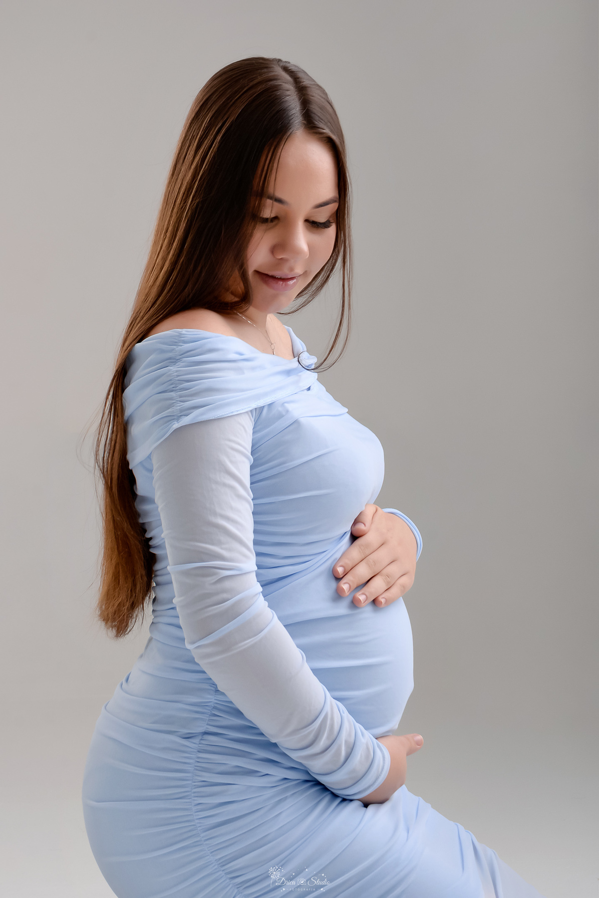 Ensaio gestante - ensaio em estudio - mamãe de primeira viagem - drica studio - xinguara - pará  mamãe usando vestido azul - sentada sobre o chão - com as mãos na barriga - 