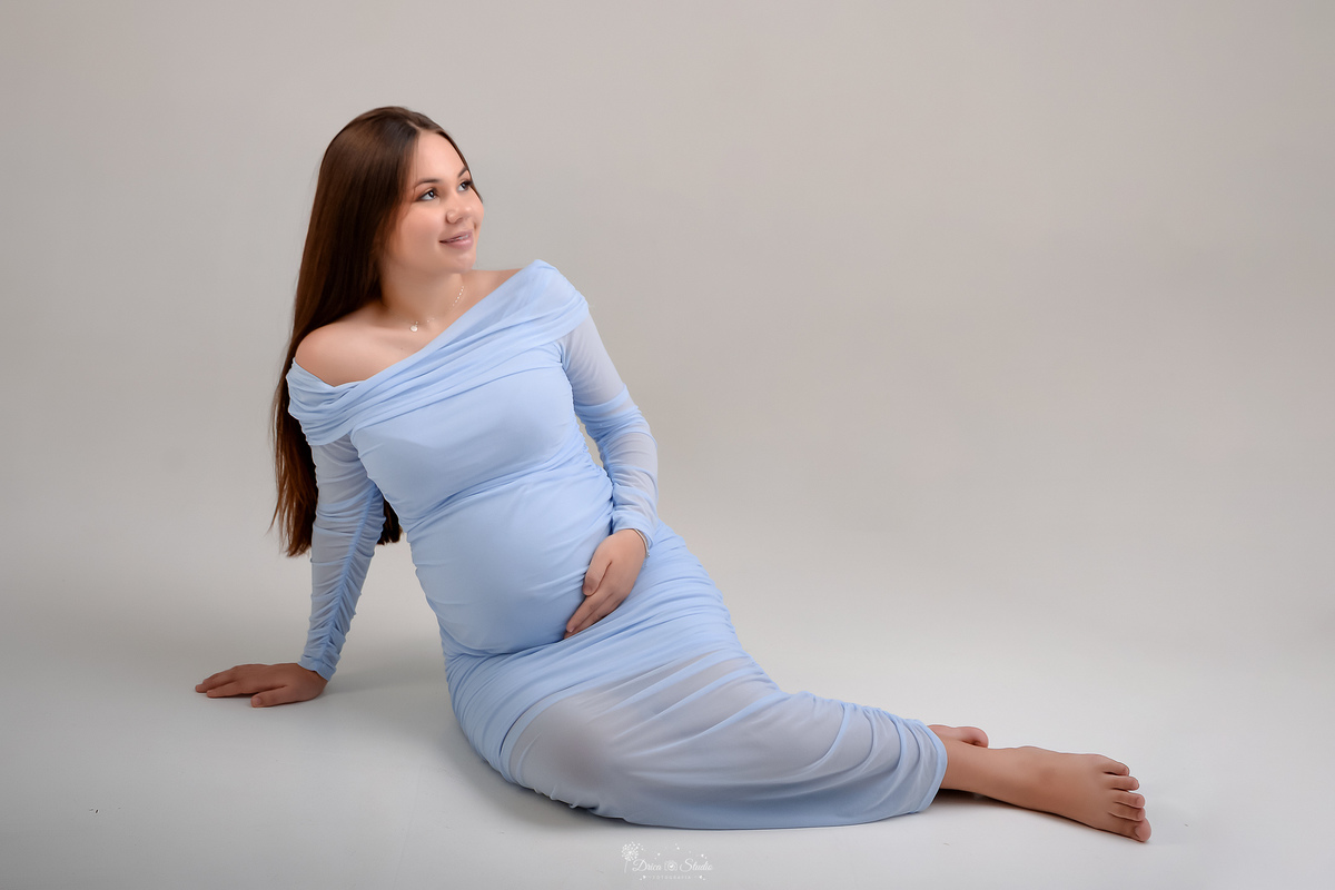 Ensaio gestante - ensaio em estudio - mamãe de primeira viagem - drica studio - xinguara - pará  mamãe usando vestido azul - sentada sobre o chão - com as mãos na barriga - 