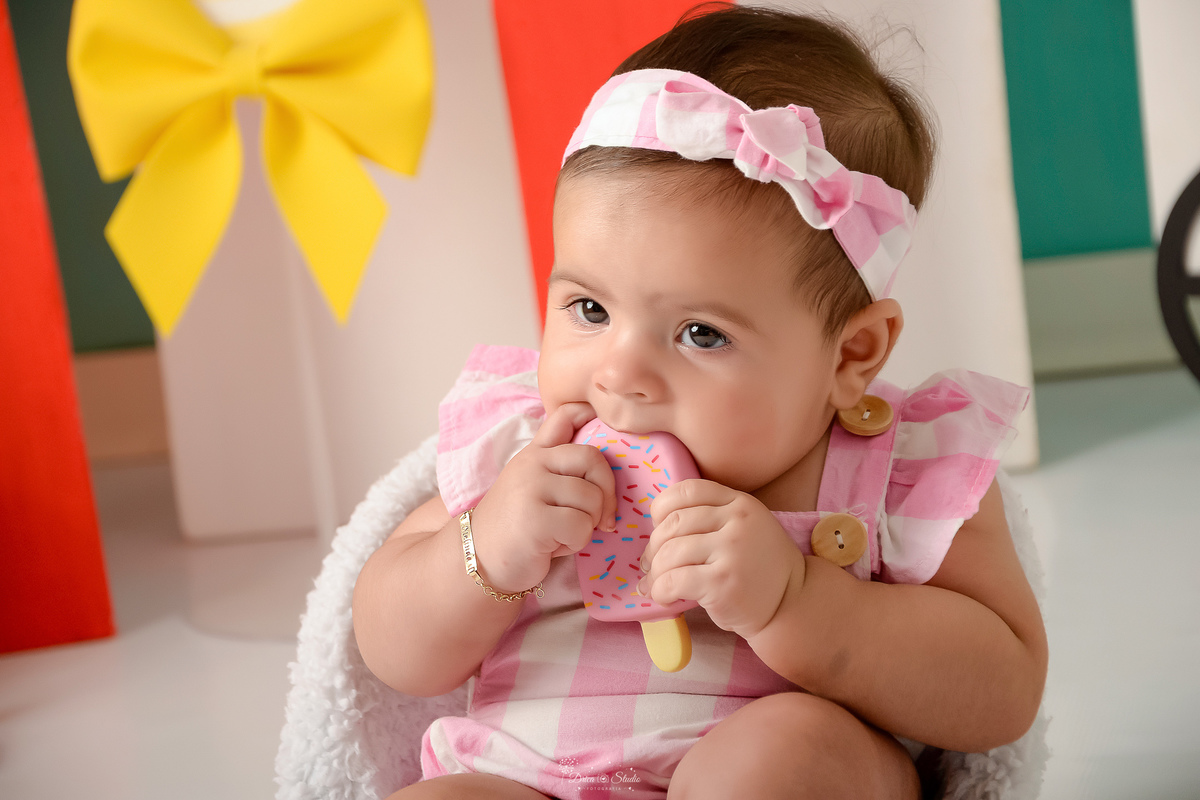 ompanhamento mensal - dia das crianças - cenário doce - mês das crianças - cenário com tematica doce - bebe usando roupinha rosa - comendo um picole de brinquedo 