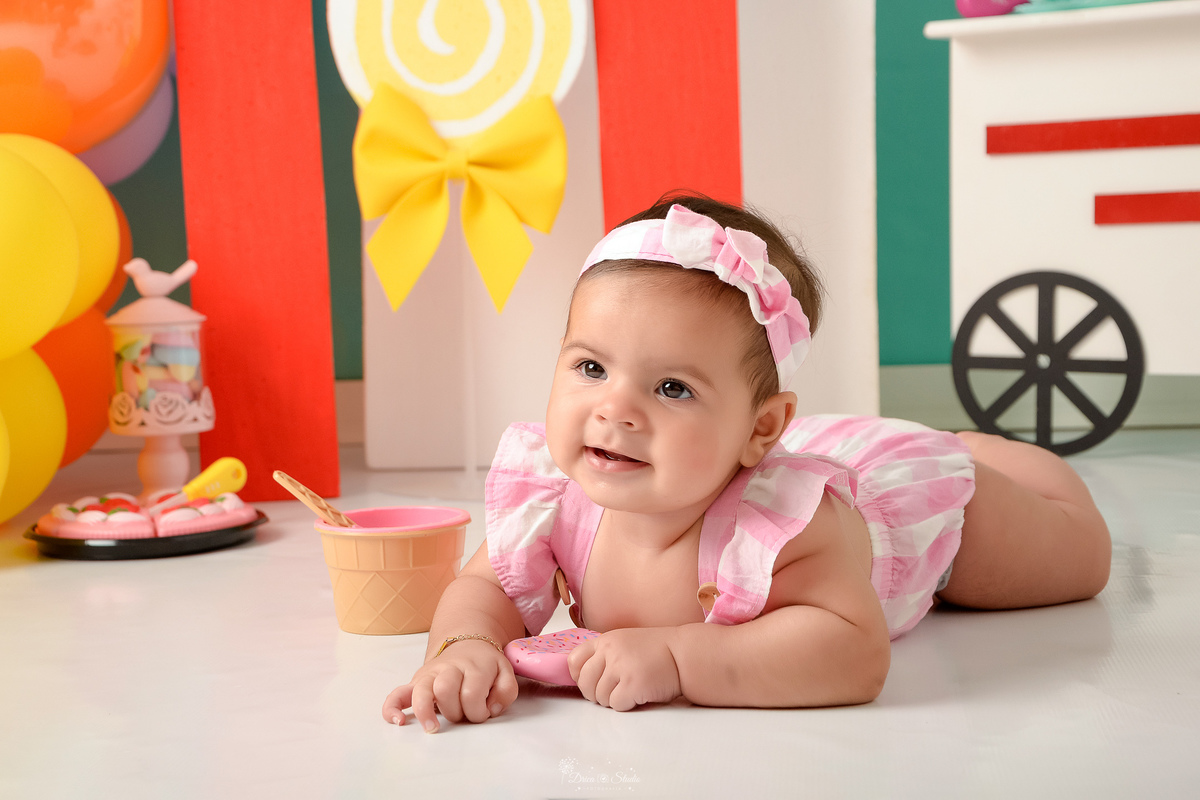 ompanhamento mensal - dia das crianças - cenário doce - mês das crianças - cenário com tematica doce - bebê deitado no cenário - usando roupinha rosa com lacinho rosa na cabeça - 