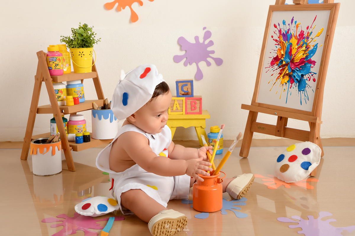 acompanhamento infantil - cenário de aquarela - dia das crianças - mês das crianças - cenários com latas de tintas - bebe brincando com varios pinceis - marcas de tintas pelo chão e parede - lousa com pintura - bebe usando roupinha de pintor 