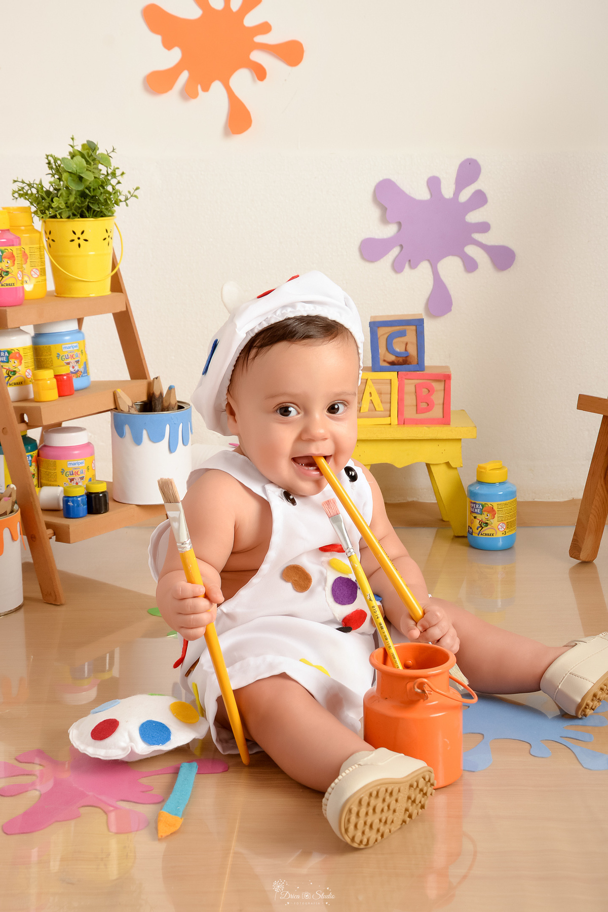 acompanhamento infantil - cenário de aquarela - dia das crianças - mês das crianças - cenários com latas de tintas - bebe brincando com pincéis - marcas de tintas pelo chão e parede - bebe usando roupinha de pintor - 