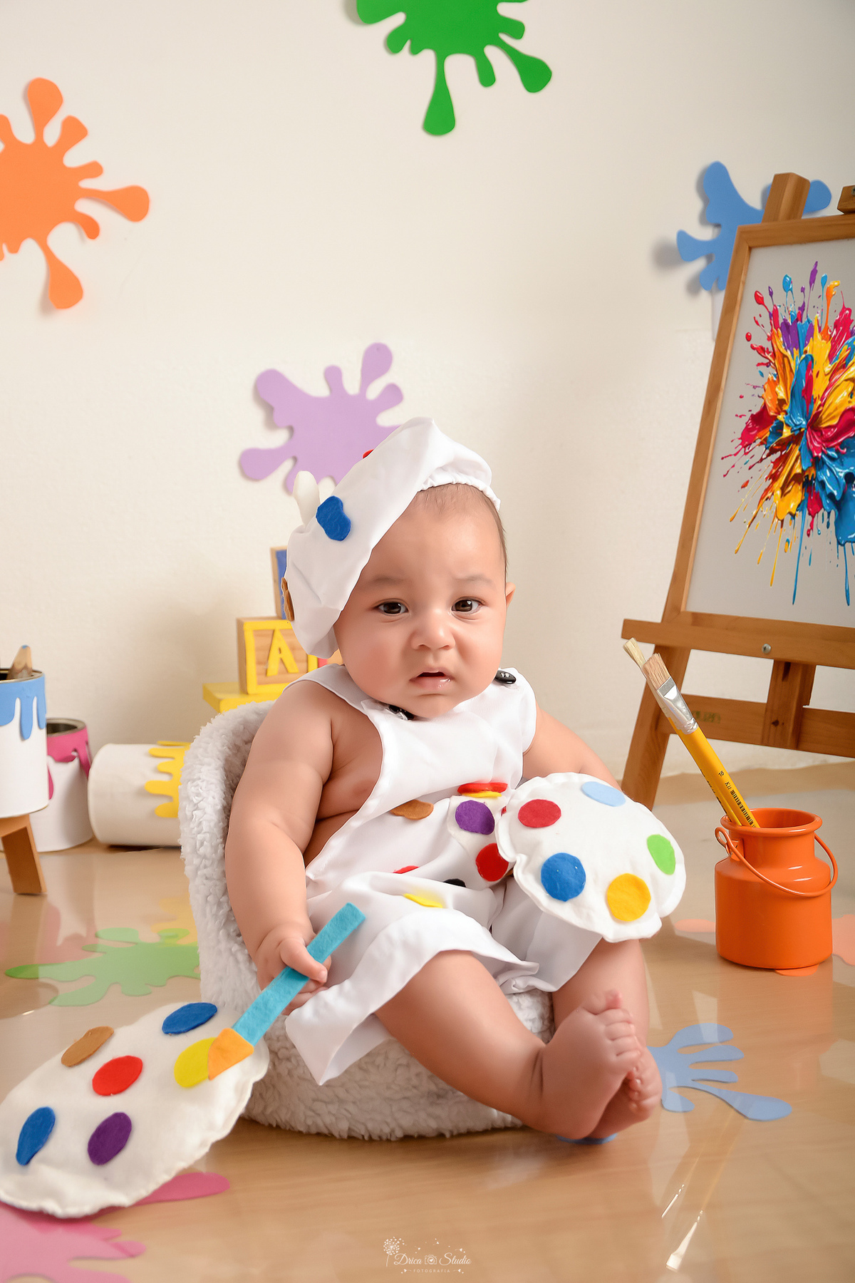 acompanhamento infantil - cenário de aquarela - dia das crianças - mês das crianças - cenários com latas de tintas - bebe usando roupinha de pintor e gorrinho na cabeça 