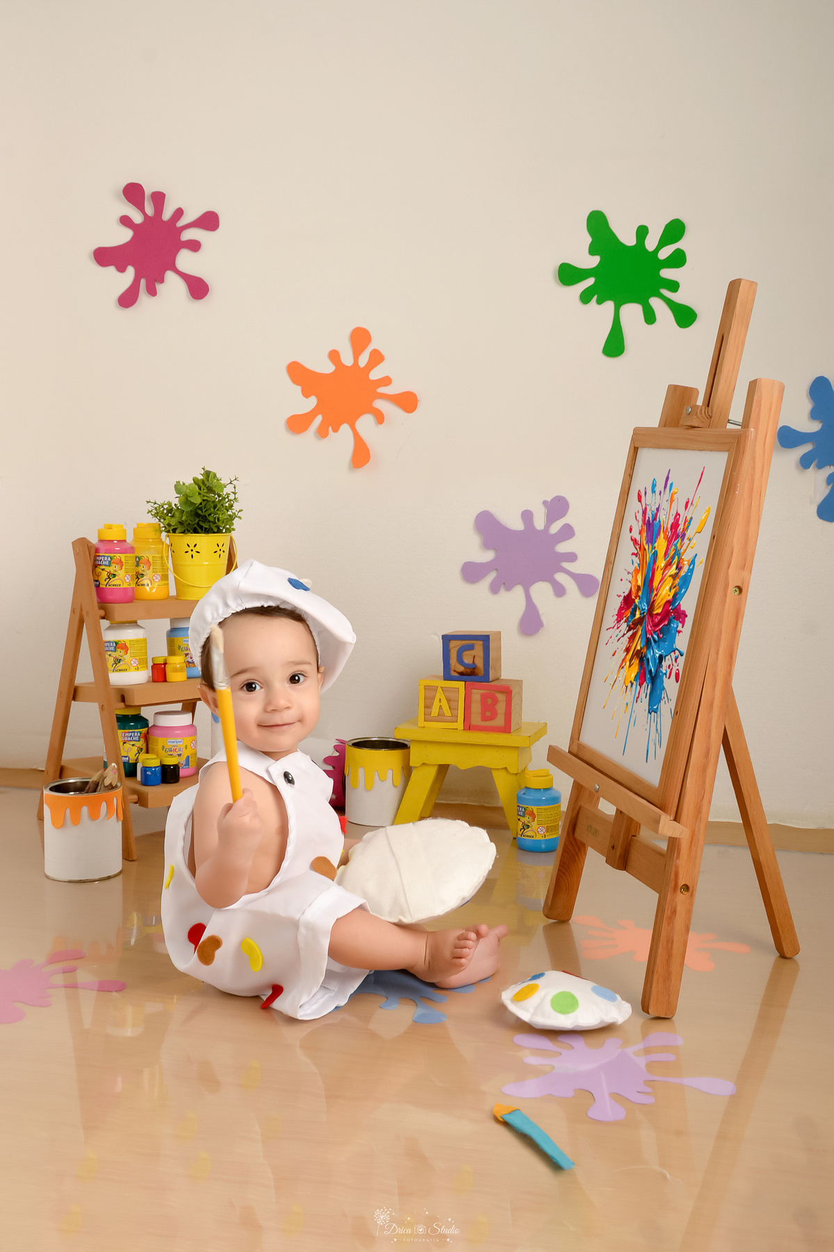 acompanhamento infantil - cenário de aquarela - dia das crianças - mês das crianças - cenários com latas de tintas - bebe segurando pincel de tinta - lousa com pintura - bebe usando roupinha de pintor e gorrinho na cabeça 