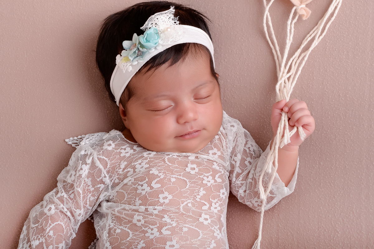 newborn - recém nascida - 11 dias de vida - primeiros dias de vida - menina - baby - usando bory branco - com tiara branca de flores - segurando minis balões - fotografia infantil - drica studio - xinguara - pará - 