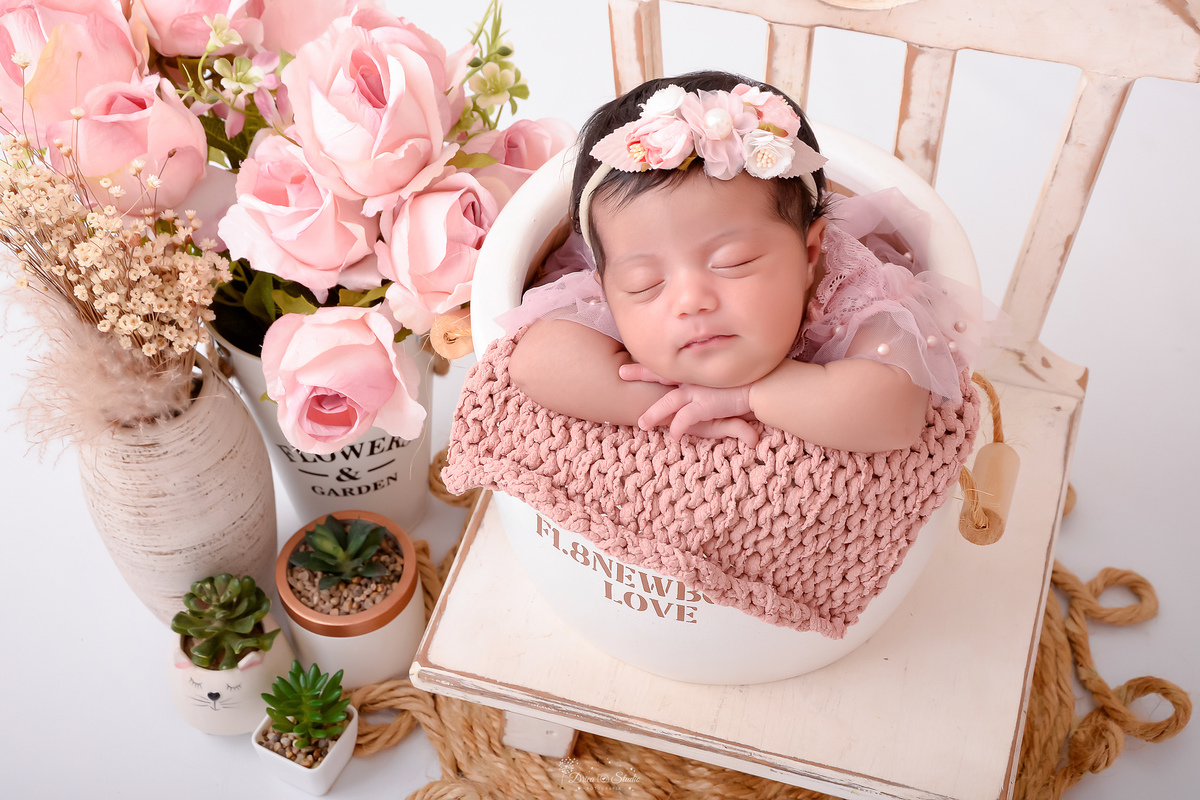 newborn - 11 dias de vida - em mini baldinho - recém nascida - usando vestido rosa - com laço de rosas - ao lado vasos de flores rosas - menina - baby - drica studio - xinguara - para 