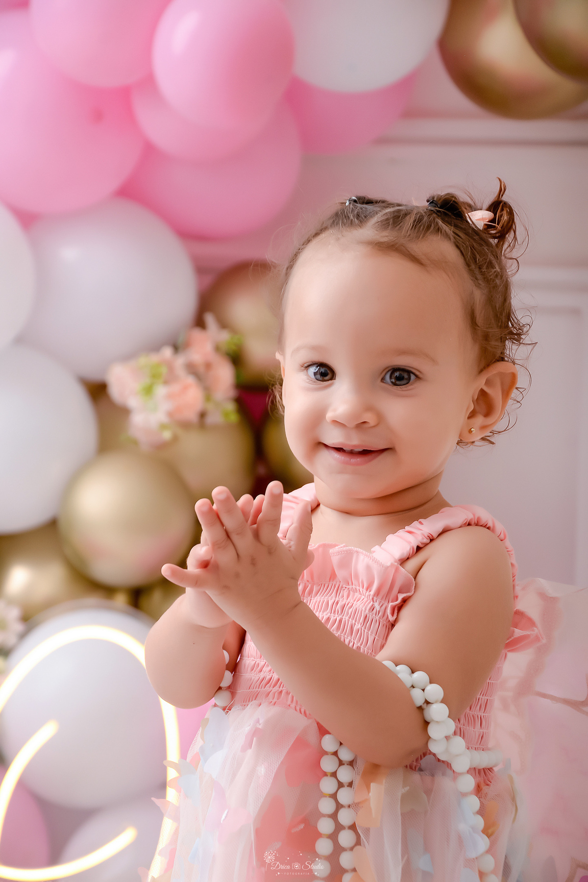 smash the cake - 1 ano - ensaio infantil - primeiro aninho - cenário com balões nas cores brancos - rosas e azuis - flores pelo cenário - bebe batendo palminhas - usando vestido na cor rosa com borboletas - drica studio - xinguara - pará -