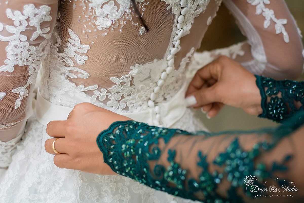 Making off foto mostra as mãos da mães da noiva finalizando o fechamento de seu vestido mostrando detalhes do vestido banco e rendado com uma fileta  de botoes.Drica Studio-Fotografias-Fotógrafo de Casamento-Xinguara-Pará- Fotografa- Making of-Casamento.