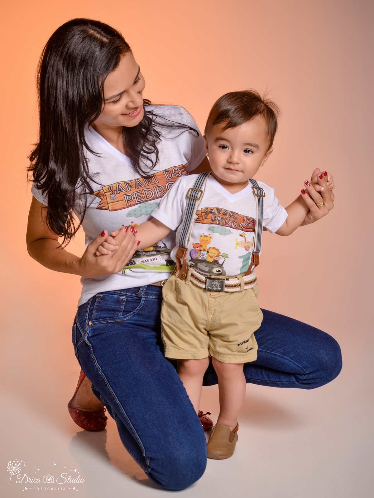 fotografia tirado em Estúdio mãe e filhos sorrindo, mãe está agachada segurando seu bebê em pé apoiado em suas mãos. Drica Studio fotografia-Fotógrafa Infantil- Fotografo em Xinguara-Fotógrafo de Criança- Ensaio Infantil- Acompanhamento de bebê- Safári