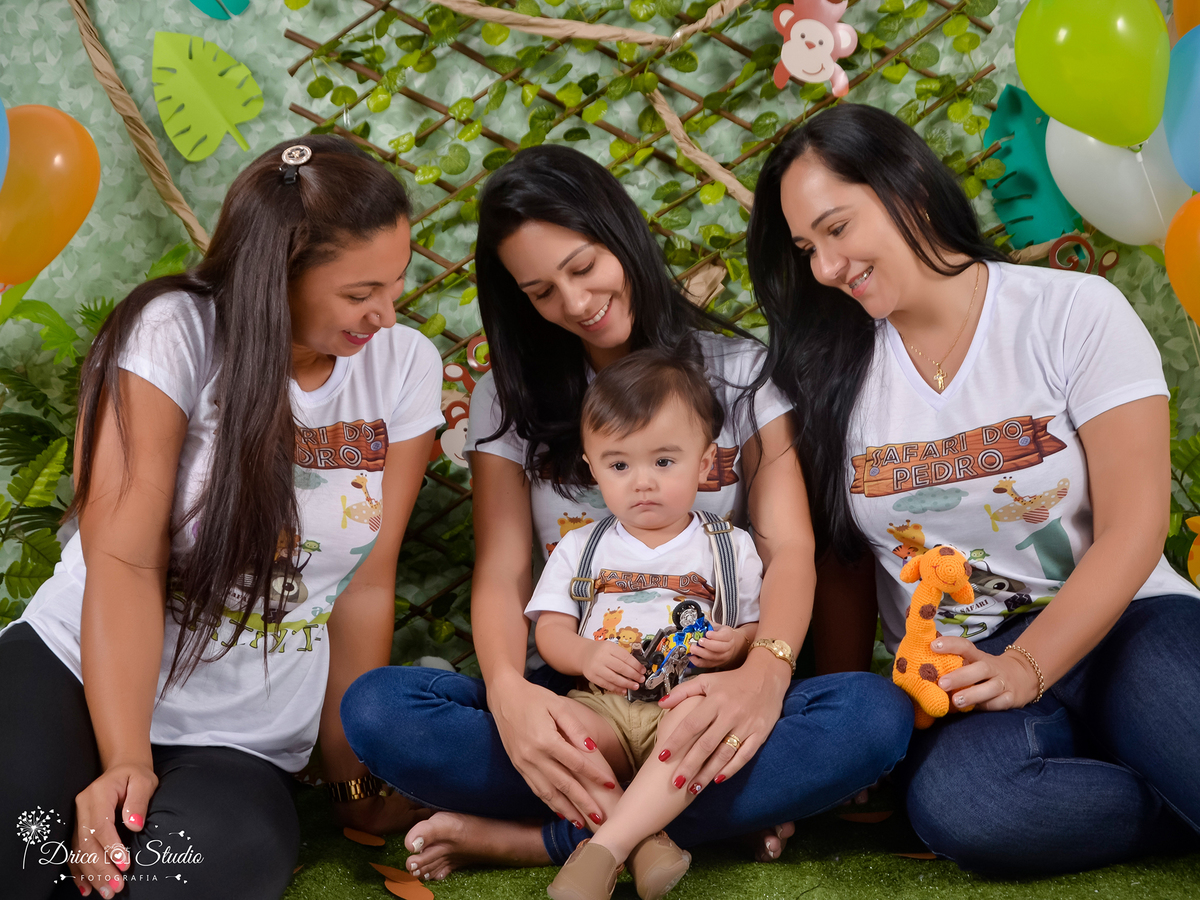 ensaio Smash mamãe sentada segurando seu bebe no colo com as madrinhas sentadas ao lado as três estão olhando para a criança, e esta serena.Fotógrafa Infantil- Fotógrafo em Xinguara-Fotógrafo de Criança- Ensaio Infantil- Acompanhamento de bebê- Safári.