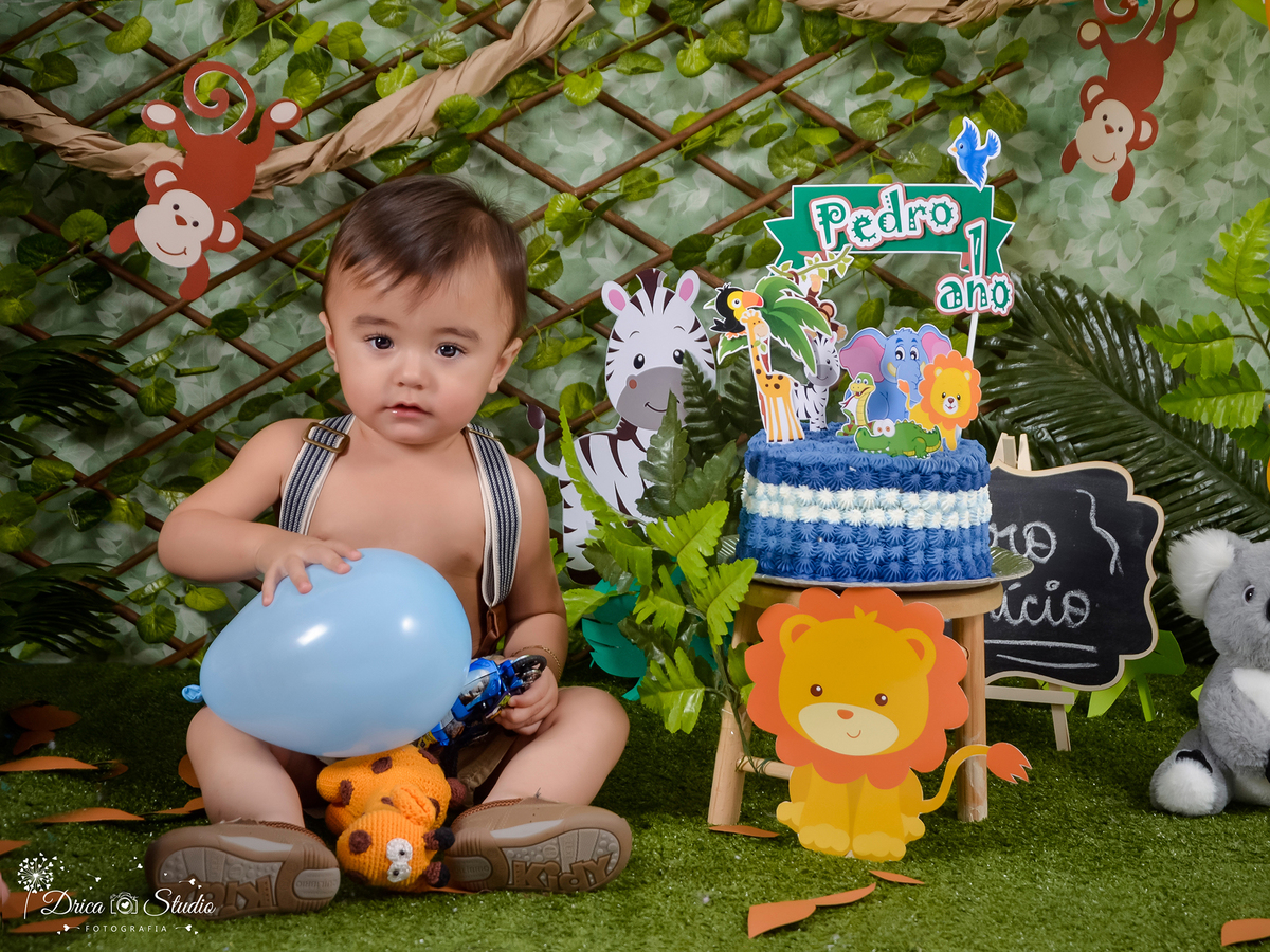 imagem demonstra uma criança sentada antes do seu Smash segurando um balão azul no senário safári e ao seu lado um bolo azul.
ensaio feito na Dricas Studio Fotografias-Fotógrafa Infantil- Fotografo em Xinguara-Fotógrafo de Criança- Ensaio Infantil-família