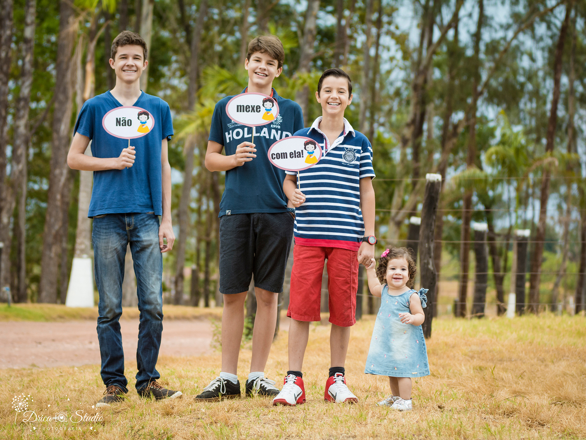 Valentina-com os irmãos-caliptolite- sorrindo -plaquinhas-não mexa com ela-vestido jeans- Xinguara- Pará- ensaio infantil- ensaio externo- ensaio de família- grama- Fotógrafa- Drica Studio-Acompanhamento- Fotografia de família- fotografa em Xinguara.