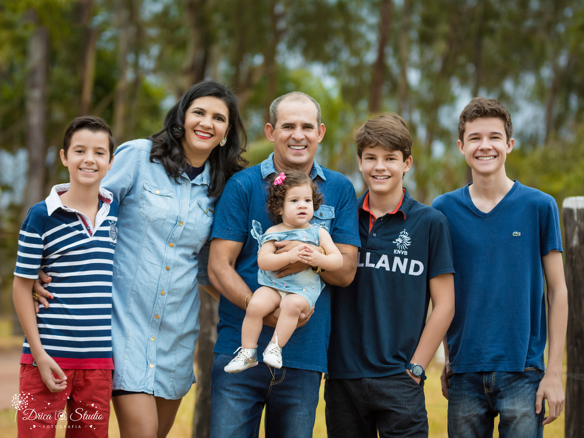 Acompanhamento- Valentina-colo da pai rodeada pela família- vestido jeans- Xinguara- Pará- ensaio infantil- ensaio externo- ensaio de família- grama- Fotógrafa- Drica Studio- Fotografia de família- fotografa em Xinguara.