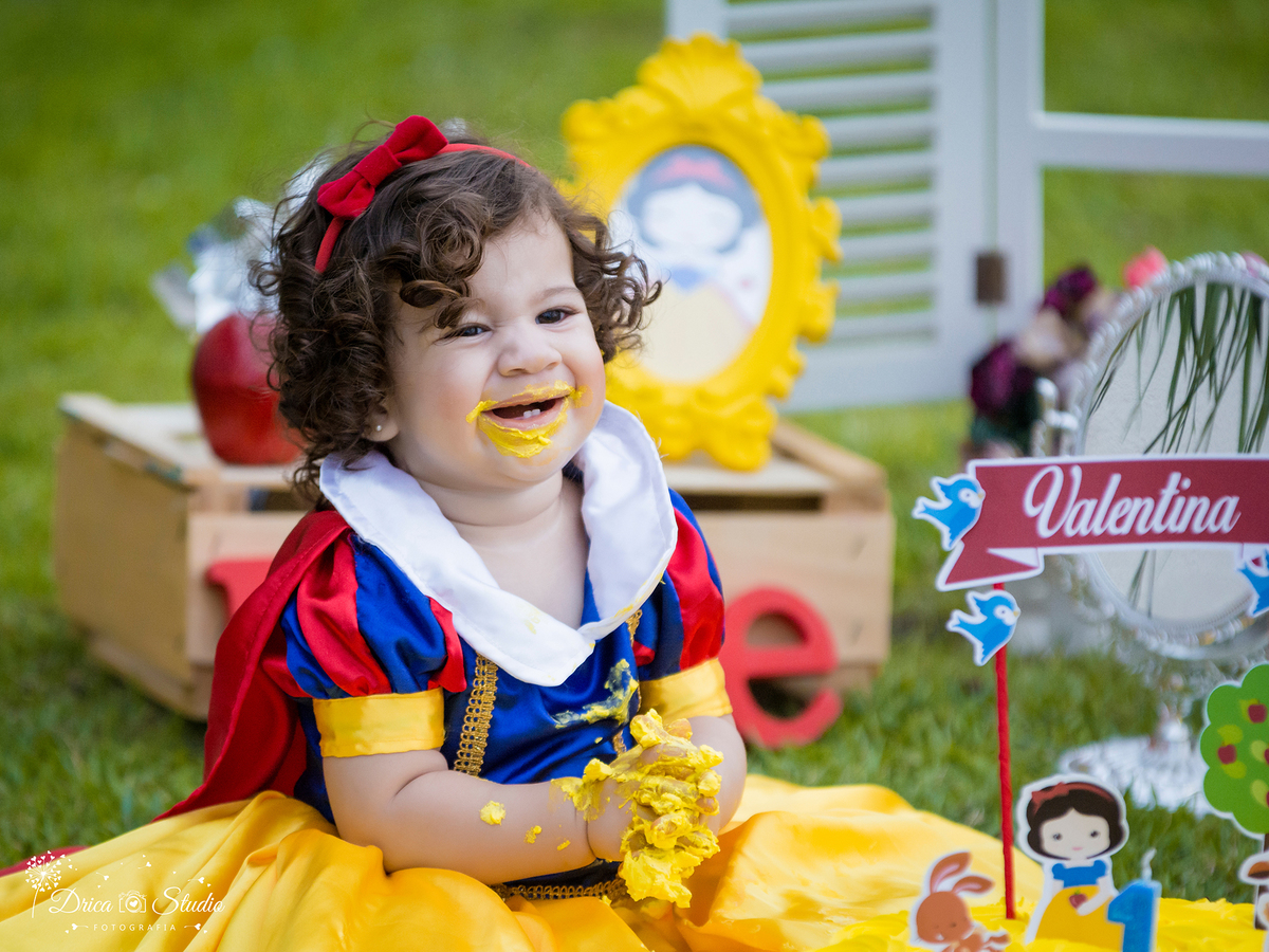  Smash the Cake- Branca de Neve- sorrindo-melada de bolo -Xinguara- Pará- ensaio infantil- ensaio externo- ensaio de família- contos de fada- grama verde- amarelo- Fotógrafa- Drica Studio- Fotografia de família- fotografa em Xinguara- cenário- lindo. 
